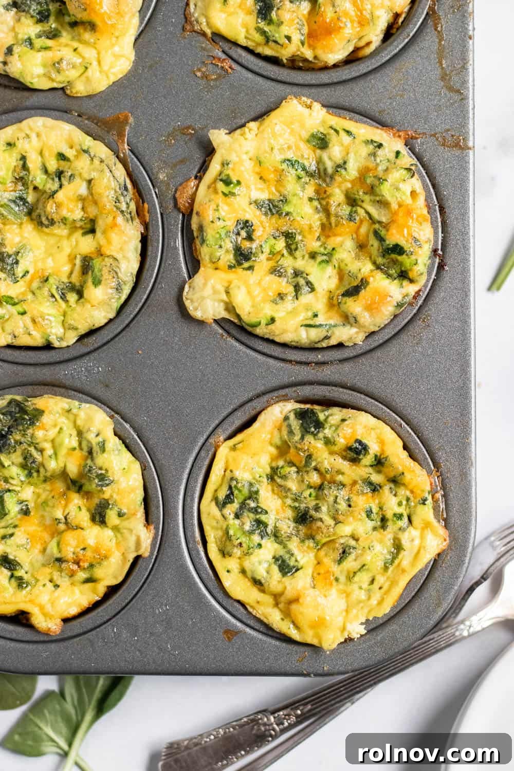 Spinach Egg Power Bites 4 Overhead view of six spinach egg muffins with zucchini, baked golden brown.