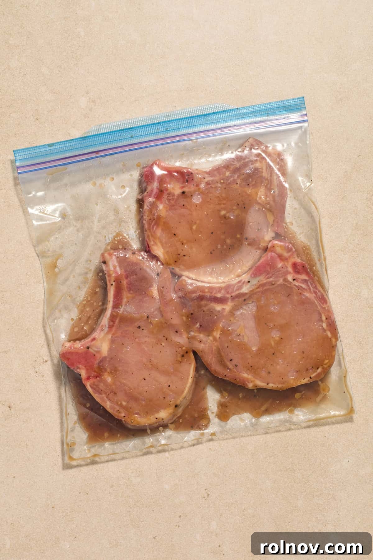 Quick & Flavorful Sheet Pan Pork Chops 4 Bone-in pork chops placed in a plastic bag, fully coated with the honey-garlic marinade and ready to rest.