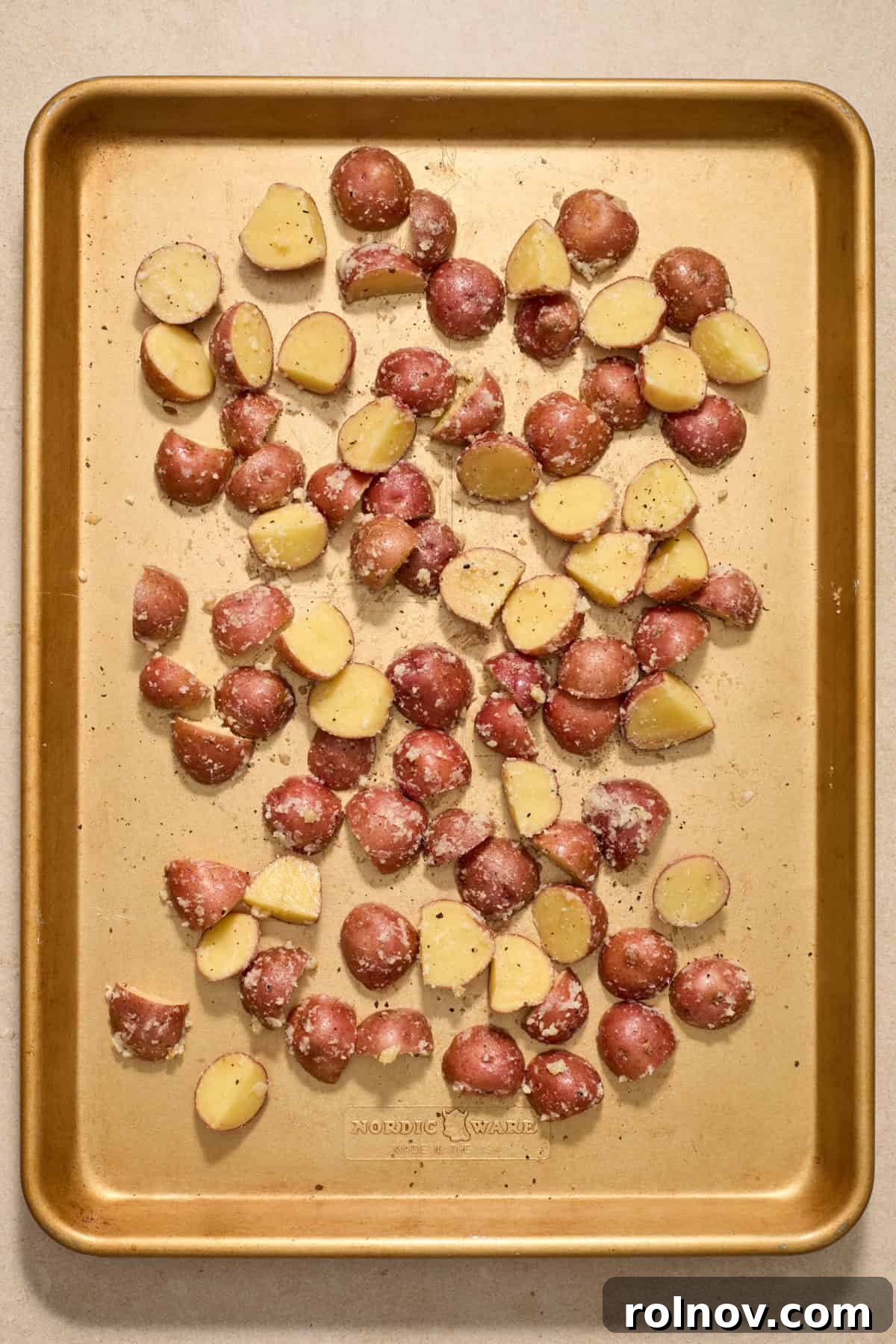 Quick & Flavorful Sheet Pan Pork Chops 6 Seasoned red potatoes spread in a single, even layer across a large baking sheet, ready for roasting.