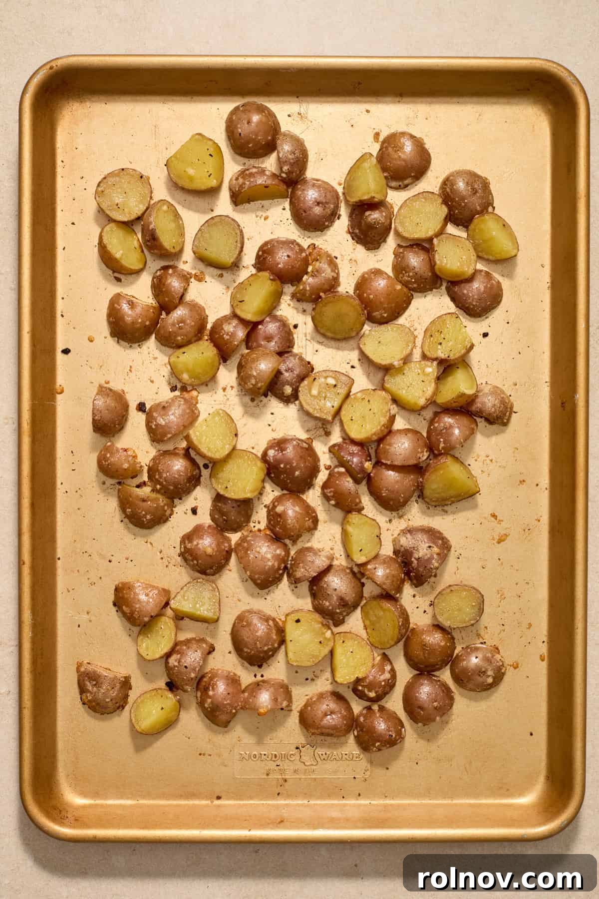 Quick & Flavorful Sheet Pan Pork Chops 7 Partially roasted parmesan potatoes on a sheet pan, showing browning and crisping edges after initial bake.