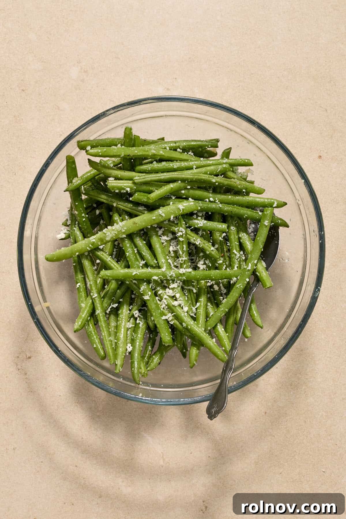 Quick & Flavorful Sheet Pan Pork Chops 8 Fresh green beans mixed with grated parmesan cheese and seasoning in a bowl, ready for roasting.