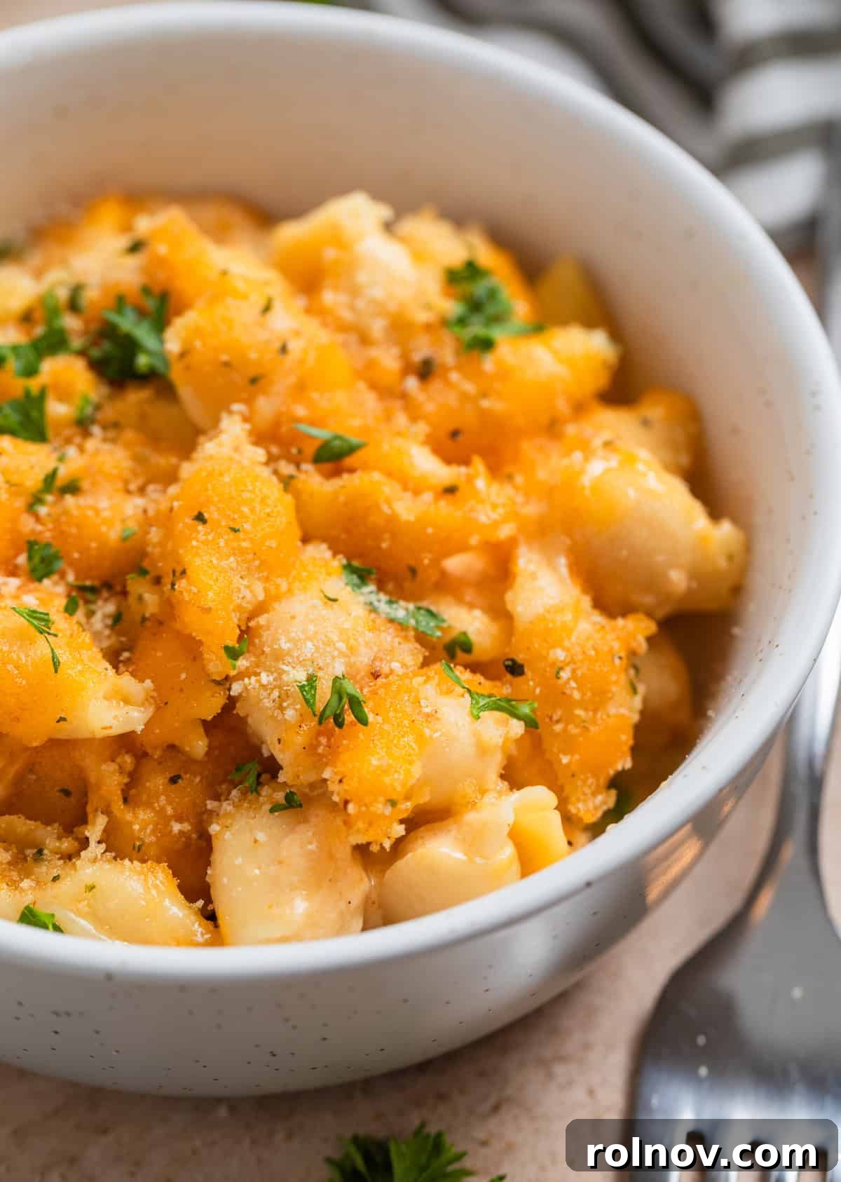 Muscle Mac 2 Creamy protein macaroni and cheese in a bowl, garnished with toasted breadcrumbs and fresh parsley, ready to be enjoyed.