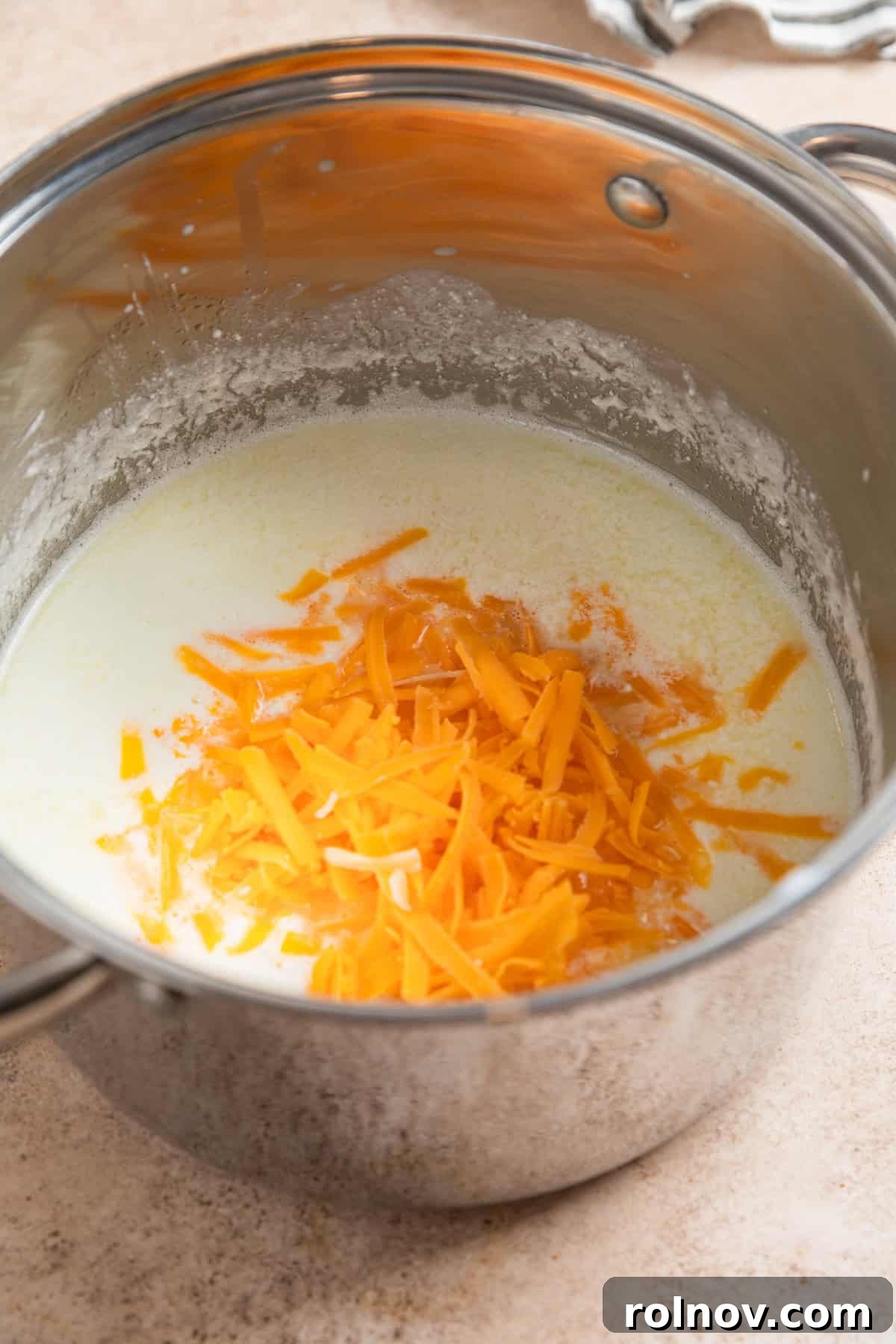 Muscle Mac 5 A pot on the stovetop contains Greek yogurt, whole milk, and shredded cheddar cheese, beginning to melt for the sauce.