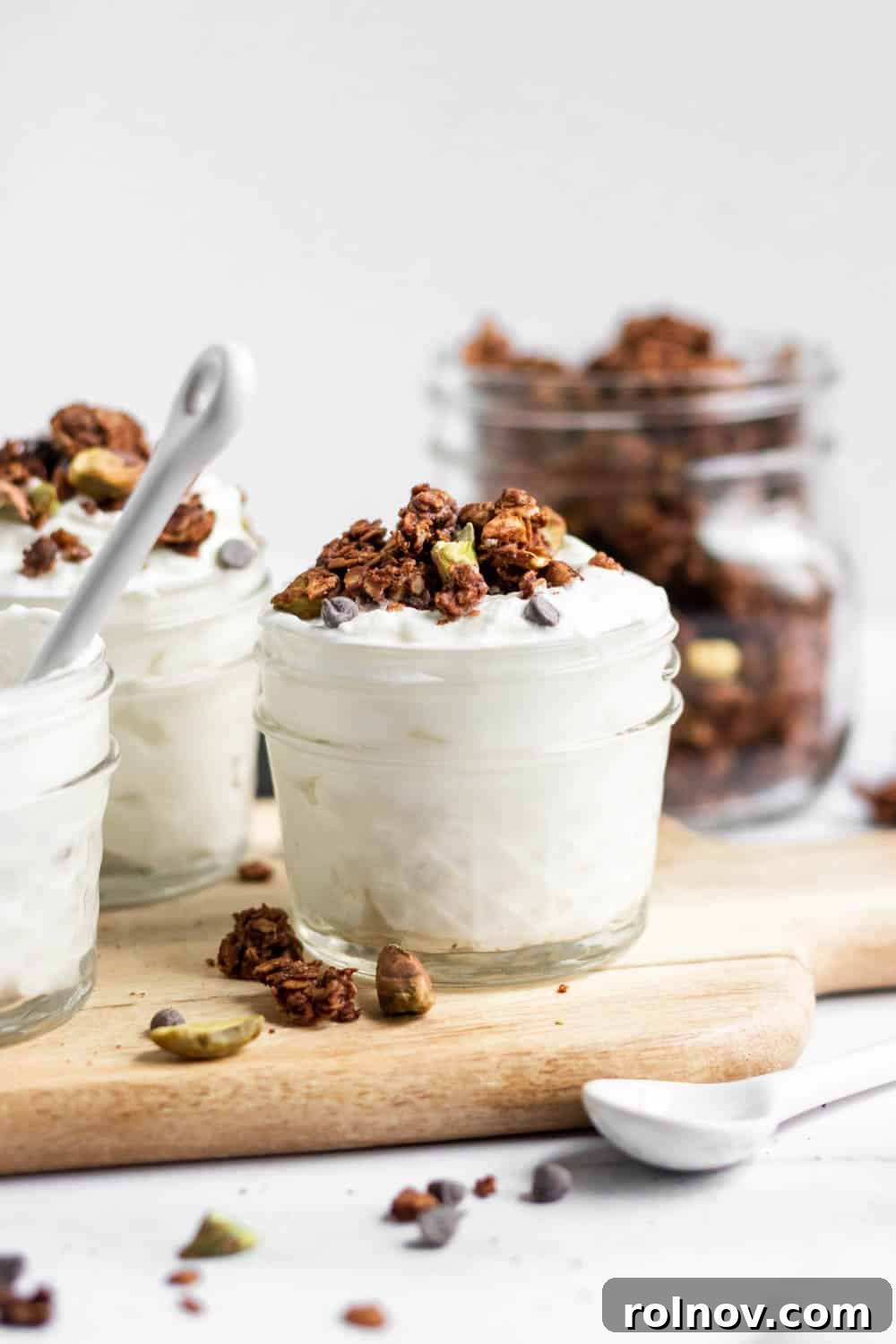 Sweet Salty Chocolate Pistachio Granola 2 Delicious homemade chocolate granola with pistachios and sea salt served in clear jars over yogurt, garnished with whole pistachios.