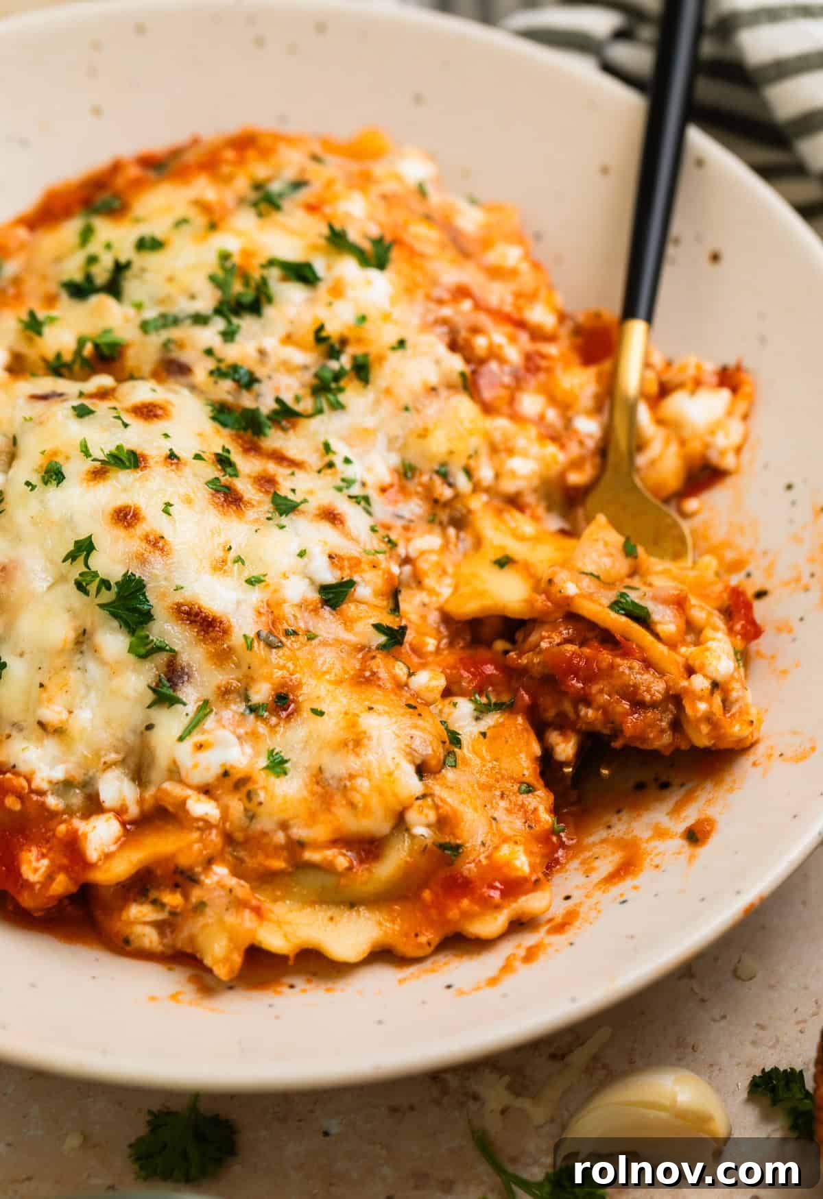 One-Pan Ravioli Lasagna 2 Plate with skillet lasagna ravioli with fork scooping in.