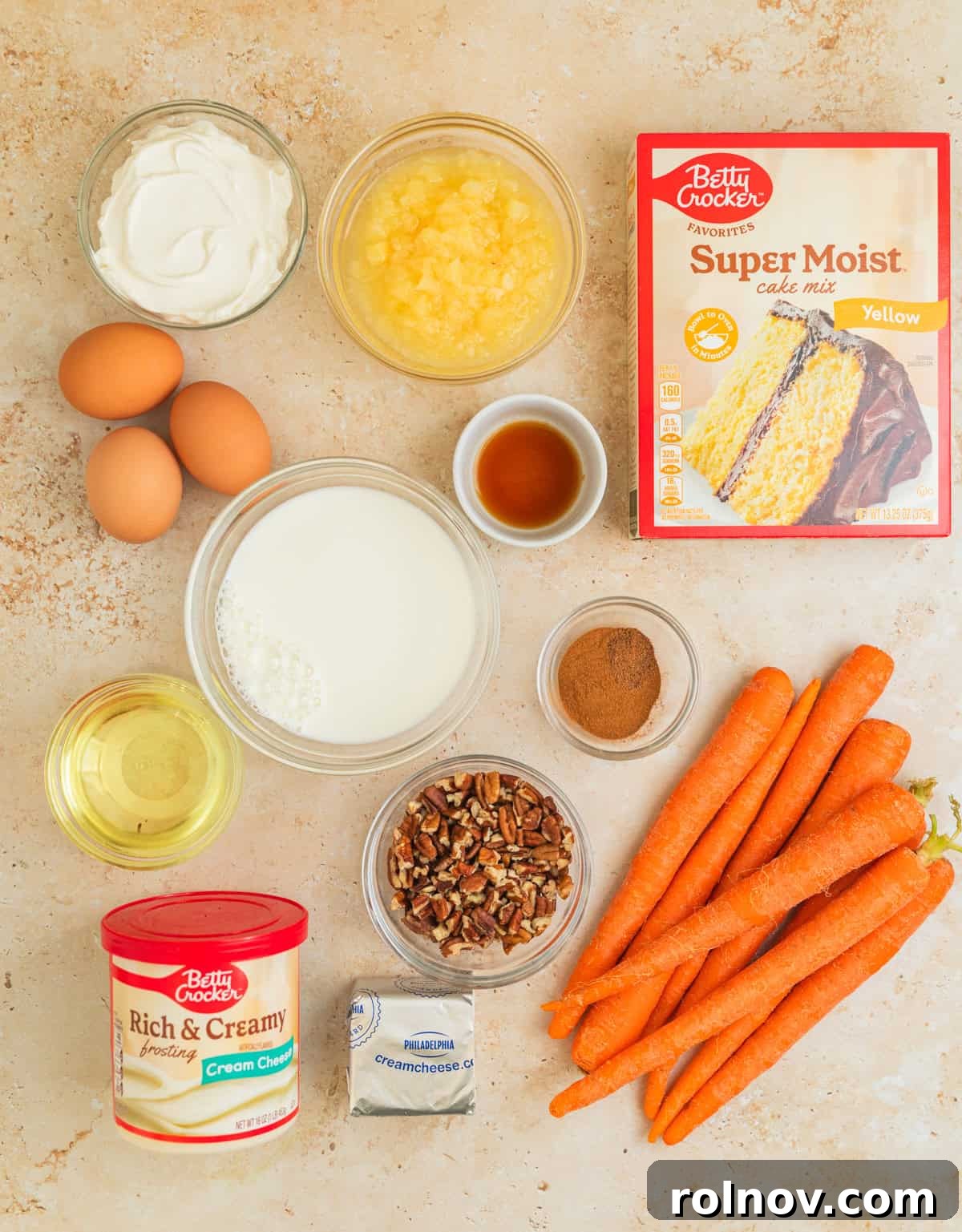 Foolproof Box Mix Carrot Cake 3 A vibrant flat lay of key ingredients for carrot cake, including a box of yellow cake mix, fresh carrots, chopped pecans, milk, and oil, arranged neatly on a rustic surface.