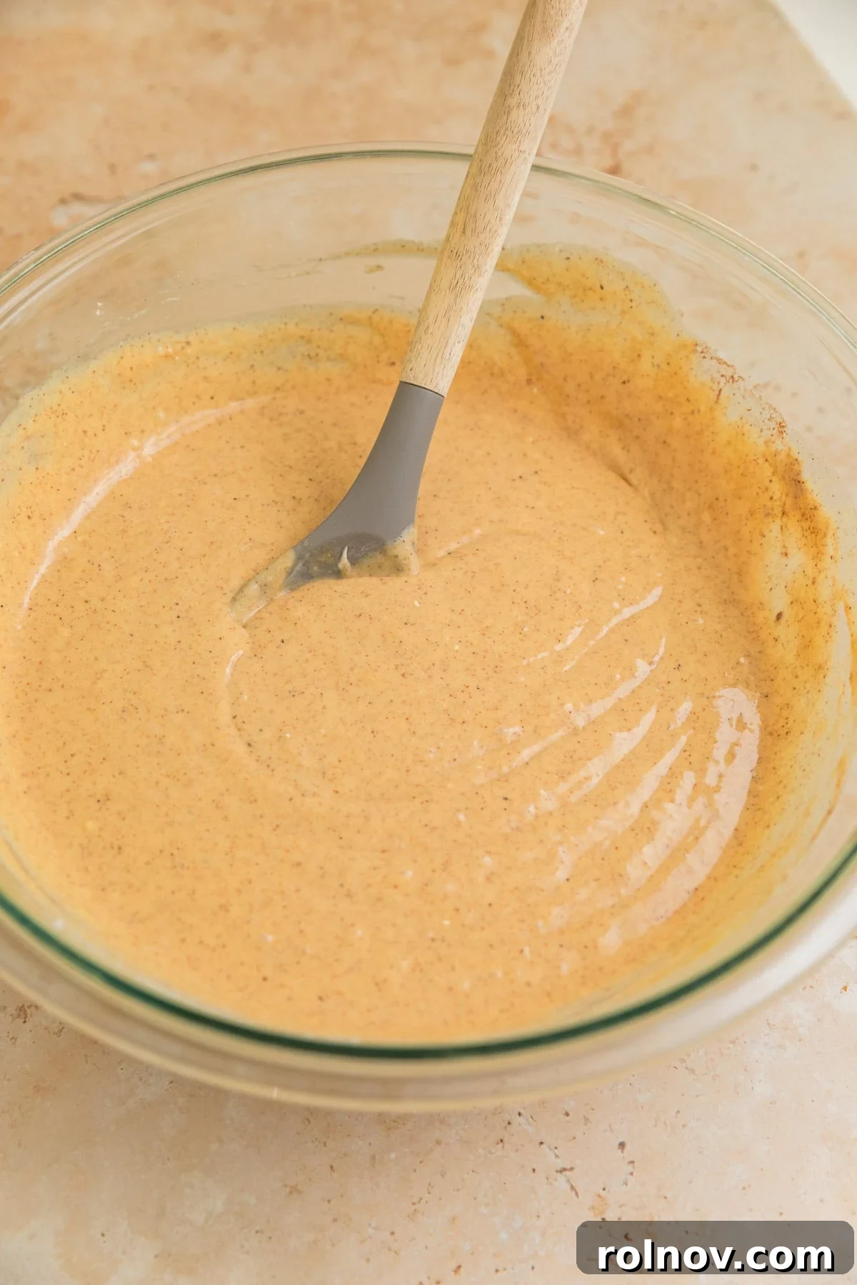Foolproof Box Mix Carrot Cake 5 Smooth, well-combined carrot cake batter in a bowl with a spoon, showing the perfectly mixed base before the addition of carrots and other textures.