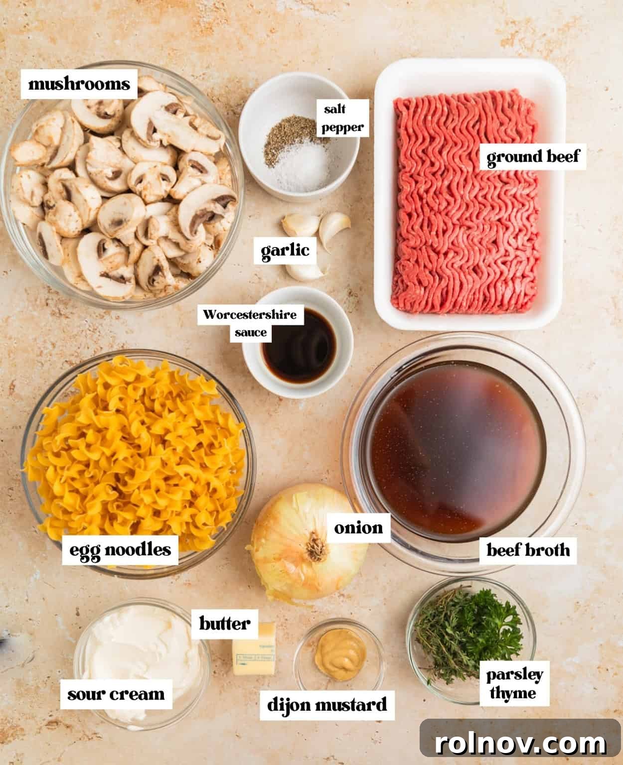 Creamy One-Pot Ground Beef Stroganoff 3 Mushrooms, beef broth, ground beef, fresh herbs and other ingredients needed to make recipe arranged on surface.