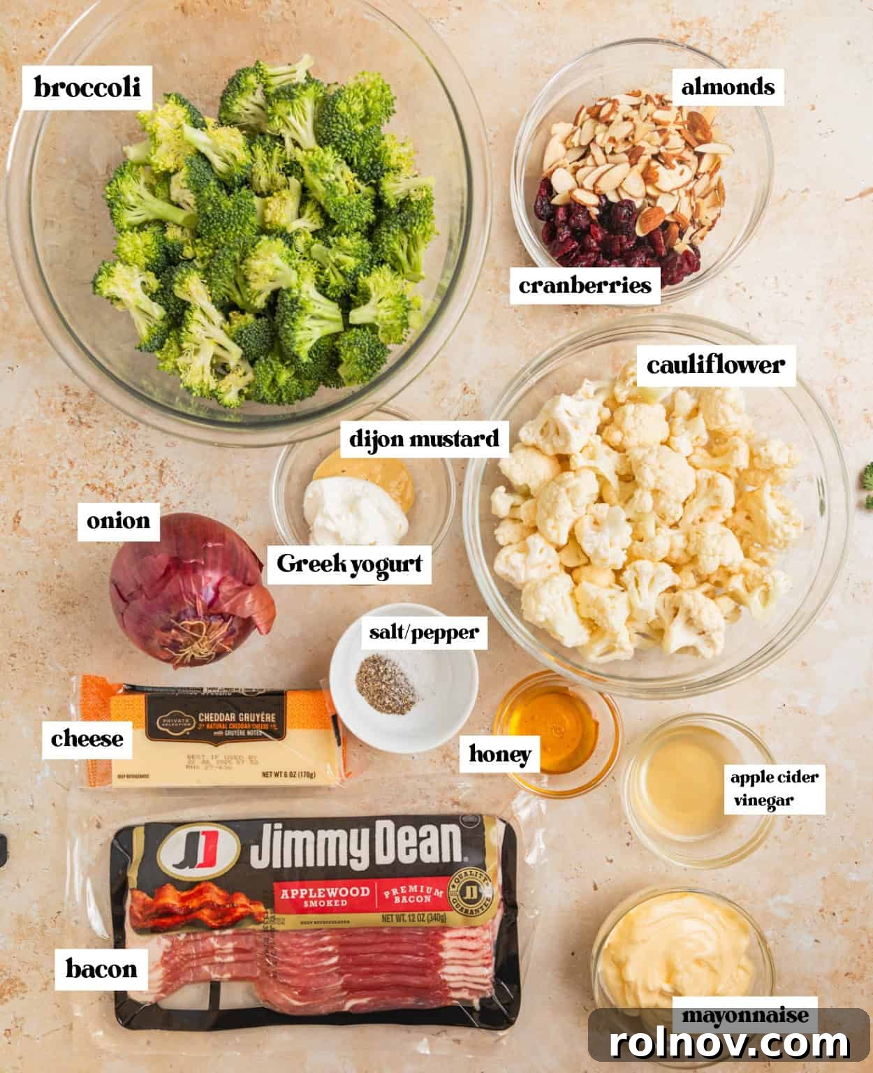 Vibrant Broccoli Cauliflower Medley 3 Fresh ingredients laid out on a surface: crispy bacon, creamy mayonnaise, sliced almonds, crisp broccoli florets, and tender cauliflower, all prepped for the salad recipe.