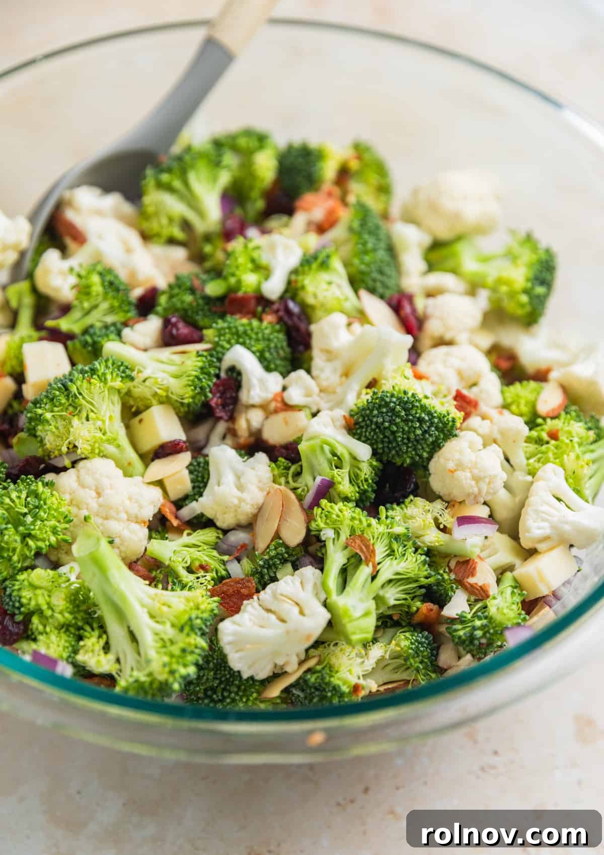 Vibrant Broccoli Cauliflower Medley 5 A large glass bowl containing all the tossed ingredients for the broccoli cauliflower salad, including vegetables, bacon, and cheese, before the dressing is added.