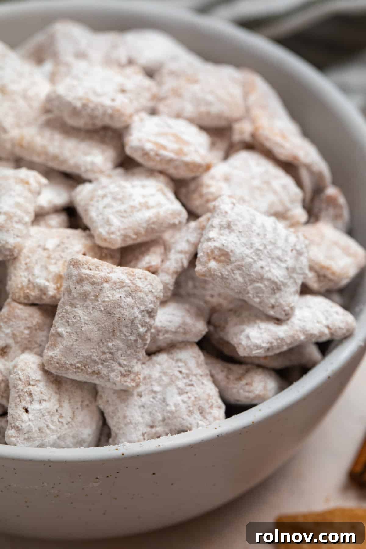 Snickerdoodle Dream Dust 2 A bowl overflowing with delicious cinnamon Chex mix generously coated in powdered sugar.