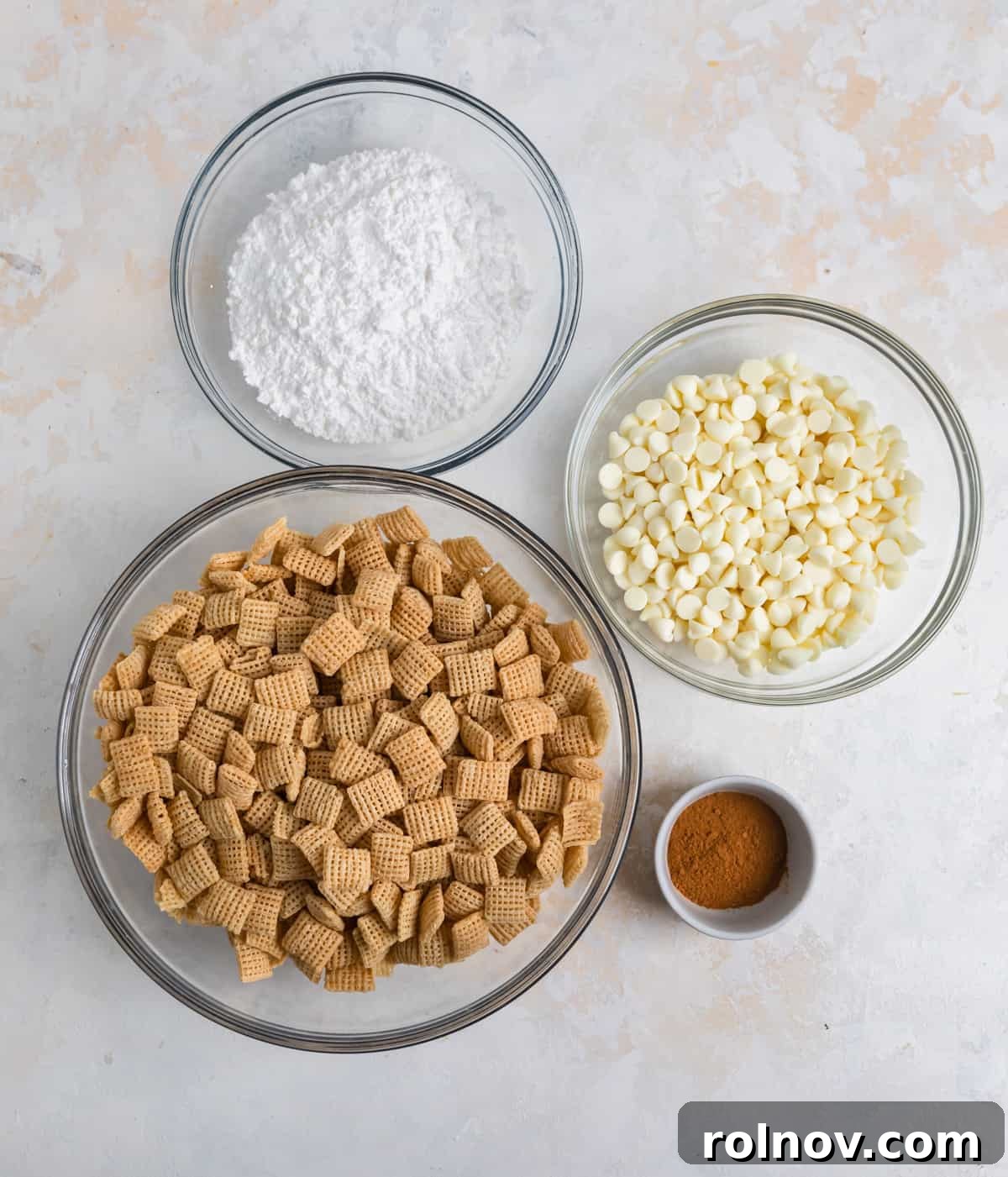 Snickerdoodle Dream Dust 3 Individual ingredients laid out on a kitchen counter: powdered sugar, white chocolate chips, ground cinnamon, and a box of Chex cereal.