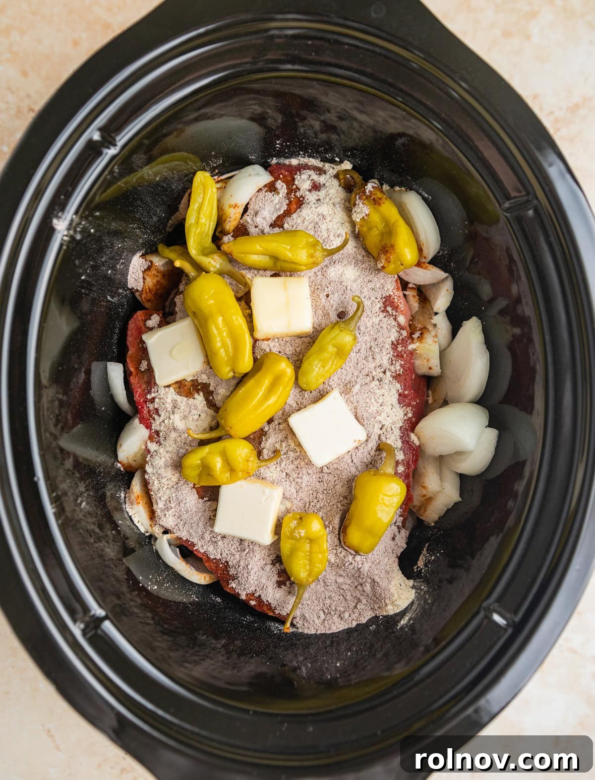 Melt-in-Your-Mouth Mississippi Pot Roast 5 Chuck roast topped with seasoning, butter and peppers in crock pot.