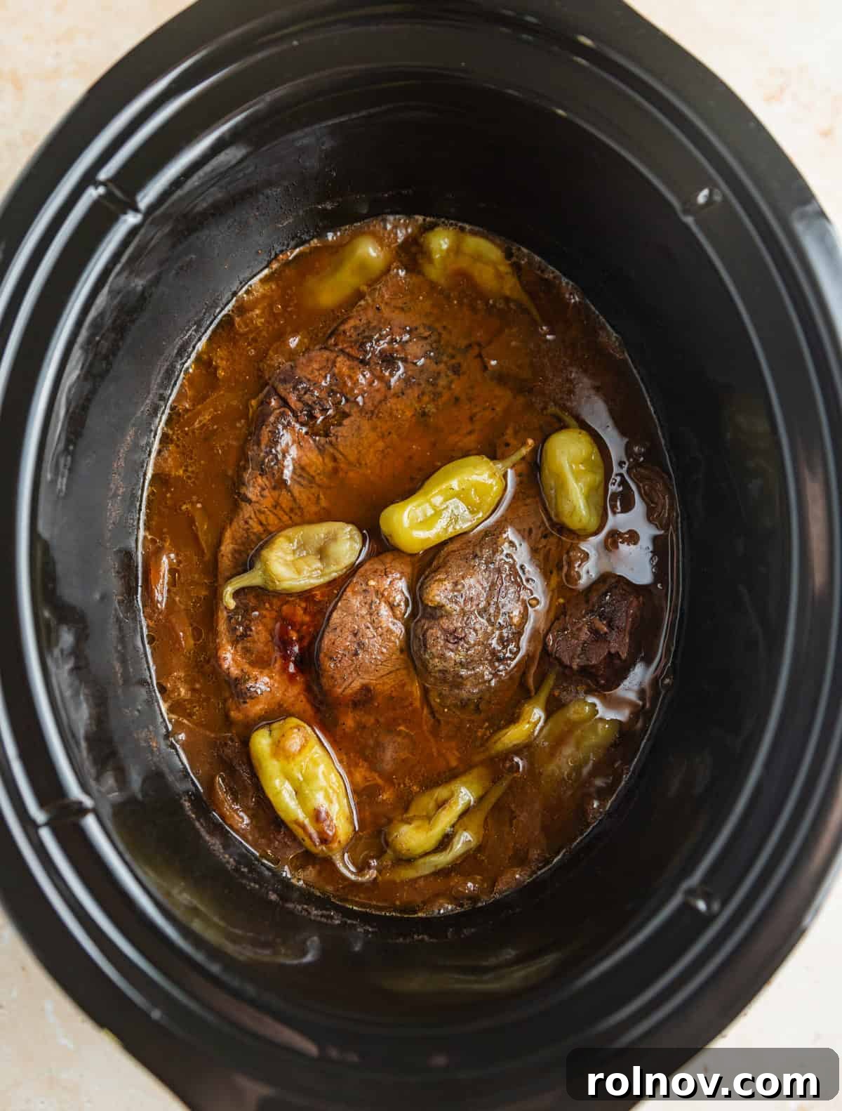 Melt-in-Your-Mouth Mississippi Pot Roast 6 Cooked pot roast in slow cooker pot with pepperoncinis.