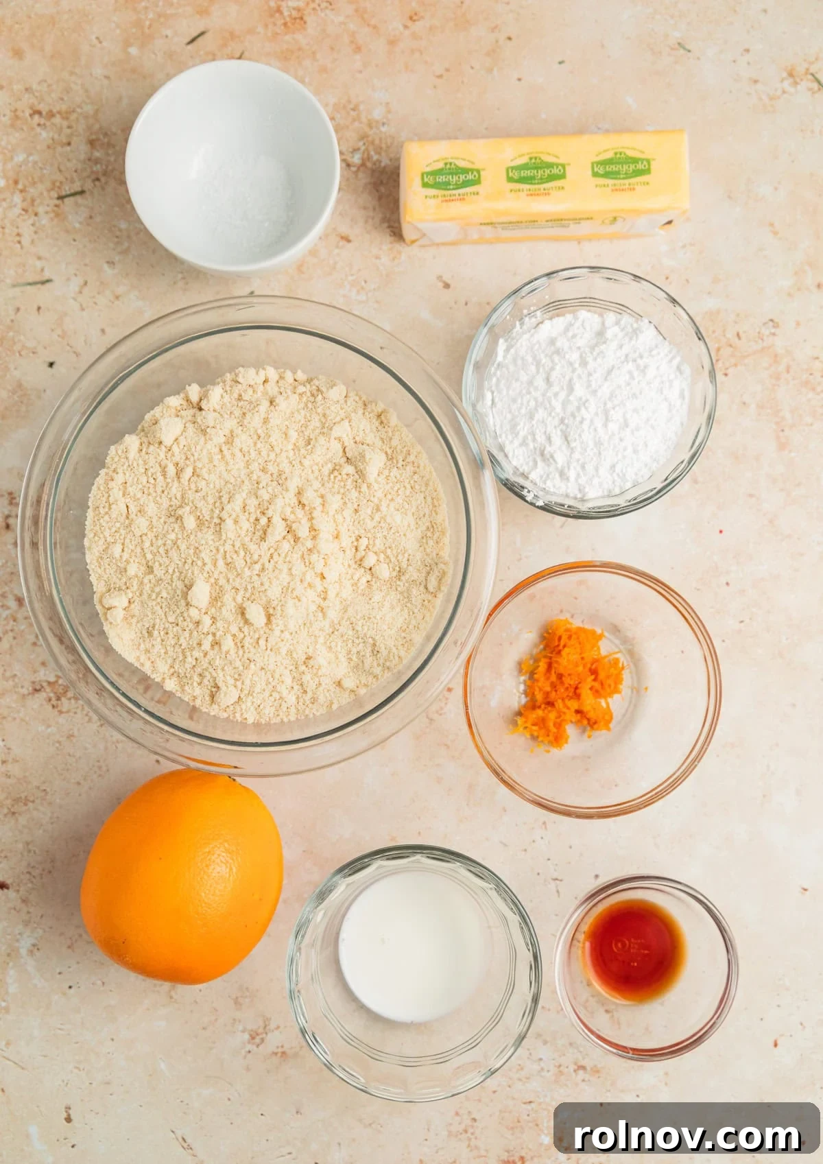 Fresh orange, orange zest, finely ground almond flour, and other baking ingredients beautifully arranged on a kitchen surface, ready for use.