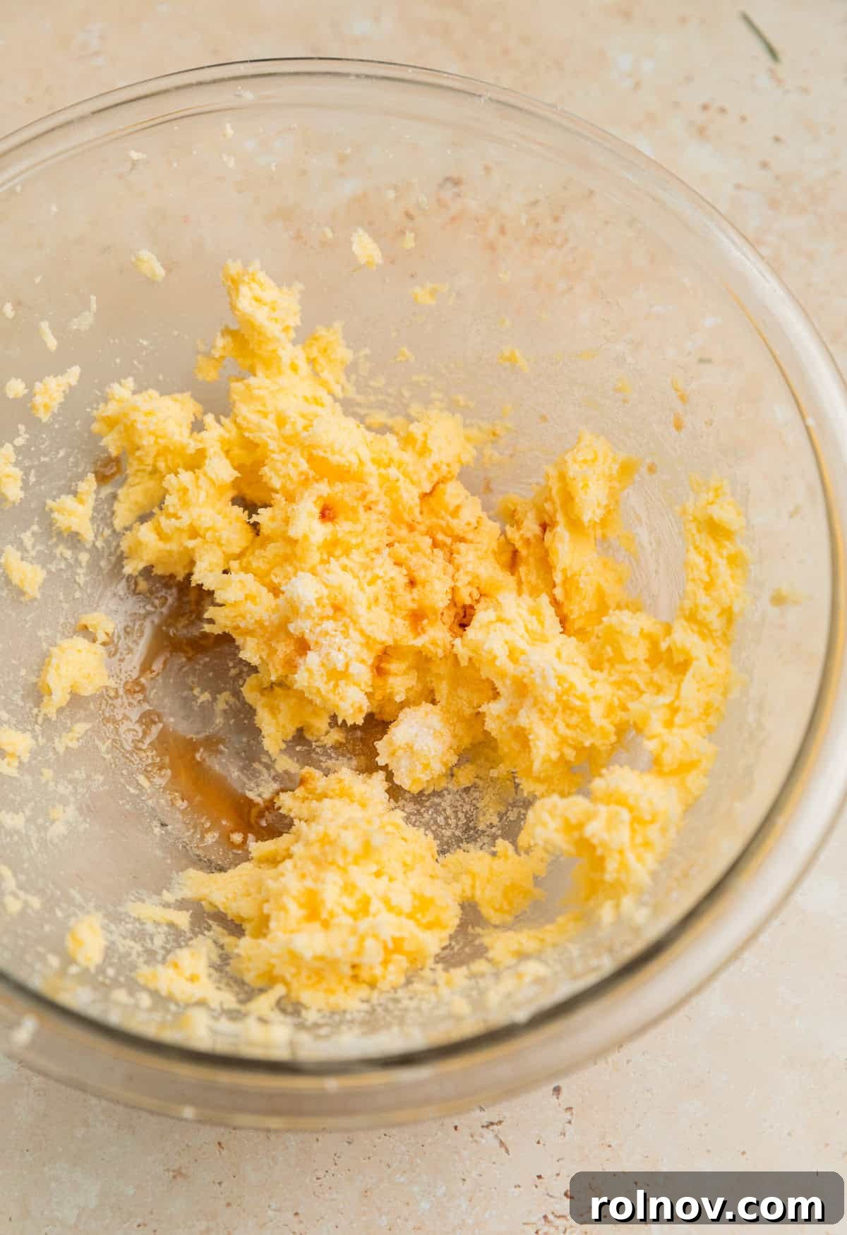 Creamed butter and sugar in a clear glass bowl, with salt and vanilla extract recently added, showing a smooth, pale mixture.