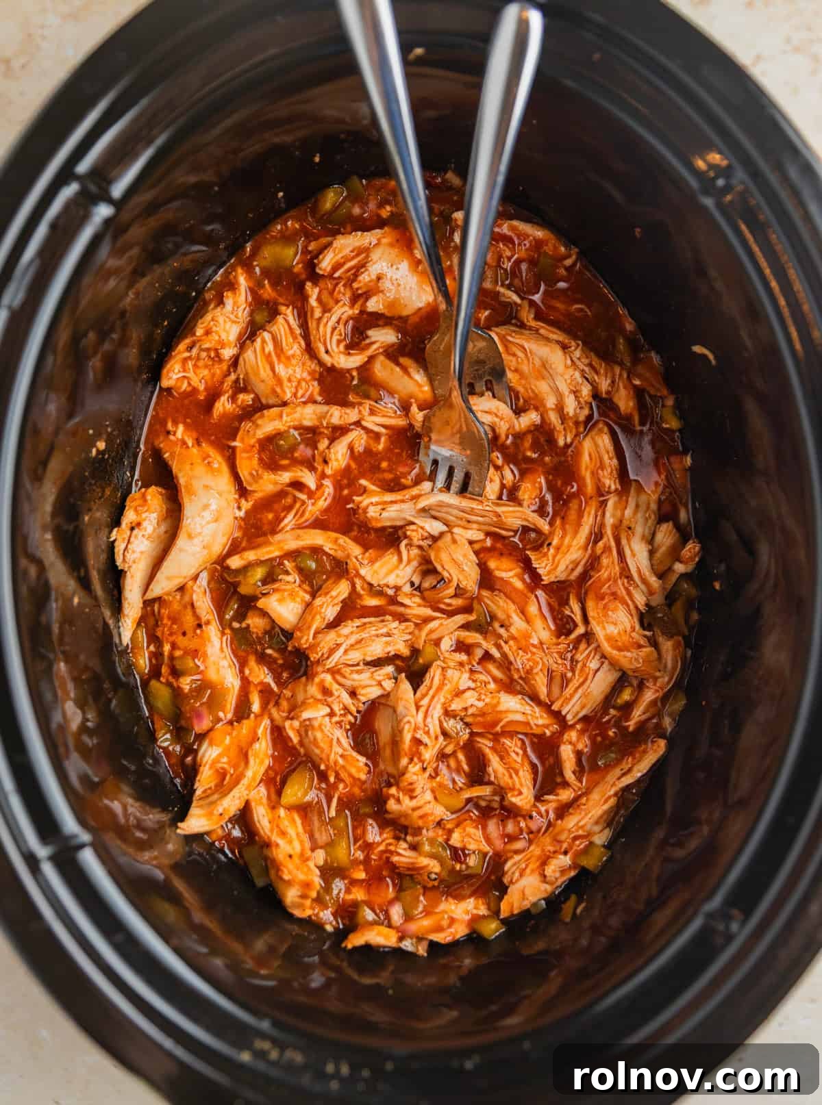 Fall-Apart BBQ Chicken Tacos with Zesty Slaw 6 Forks shredding bbq chicken breast in slow cooker pot.