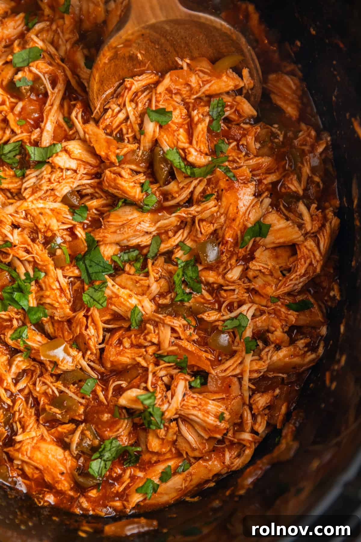 Fall-Apart BBQ Chicken Tacos with Zesty Slaw 9 Shredded bbq chicken topped with chopped cilantro in crockpot with wooden spoon scooping in.