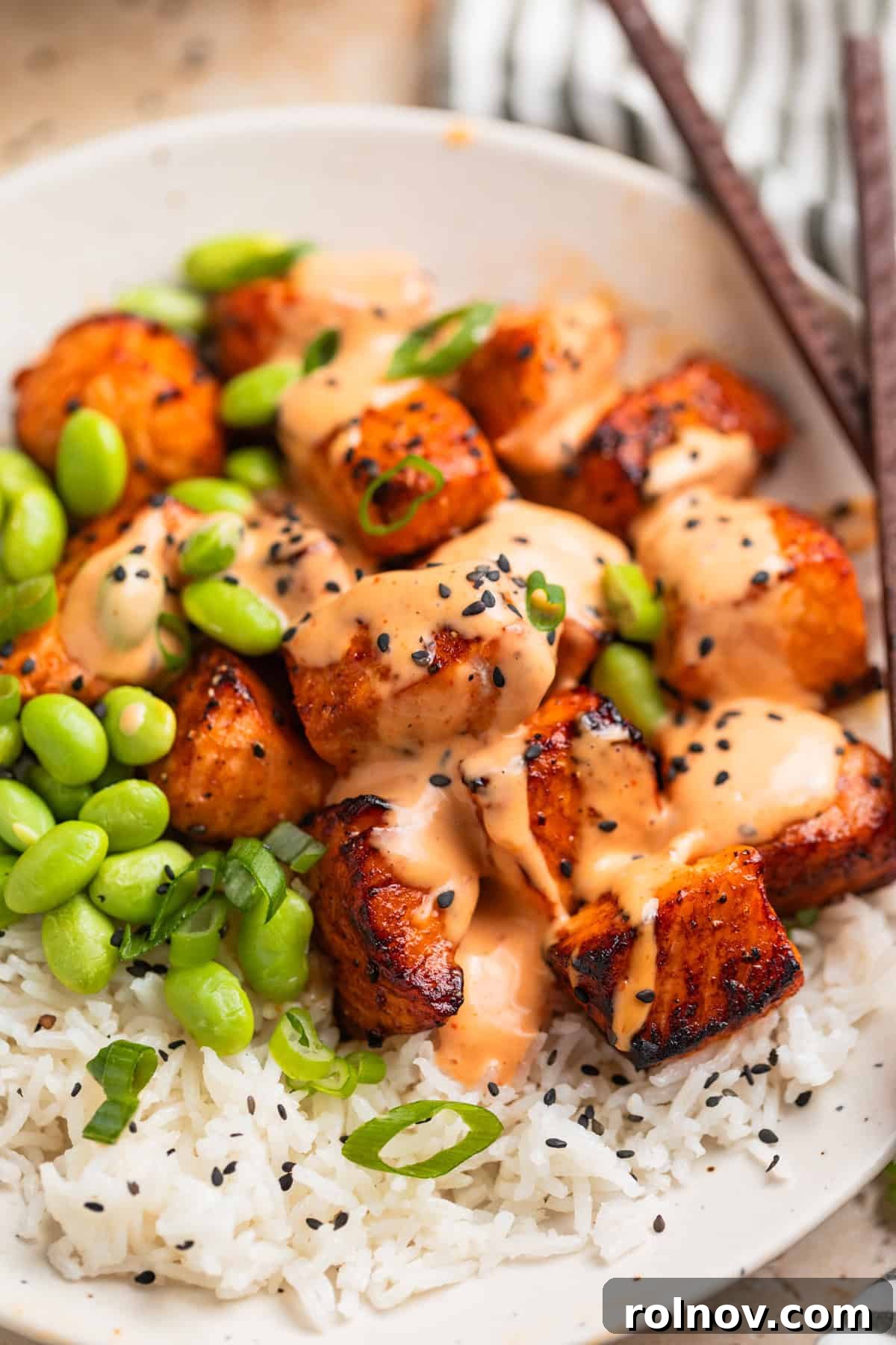 Crispy Air Fryer Salmon Bites 2 Dish with air fryer salmon bites topped with bang bang sauce and black sesame seeds.