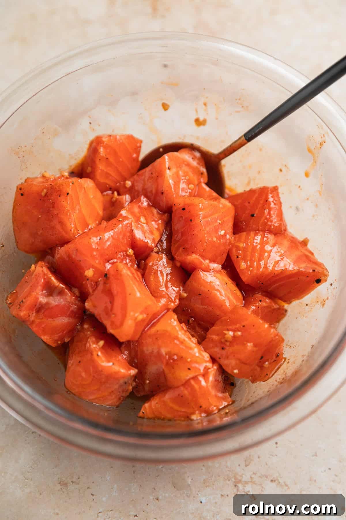 Crispy Air Fryer Salmon Bites 5 Salmon cubes in glass bowl with marinade.