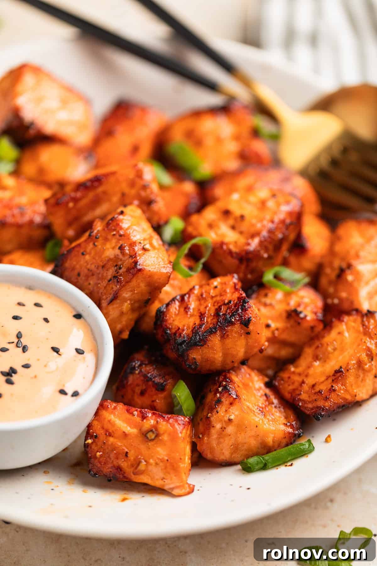 Crispy Air Fryer Salmon Bites 10 Air fried steak bites on plate topped with green onion and served with bang bang sauce in dish.