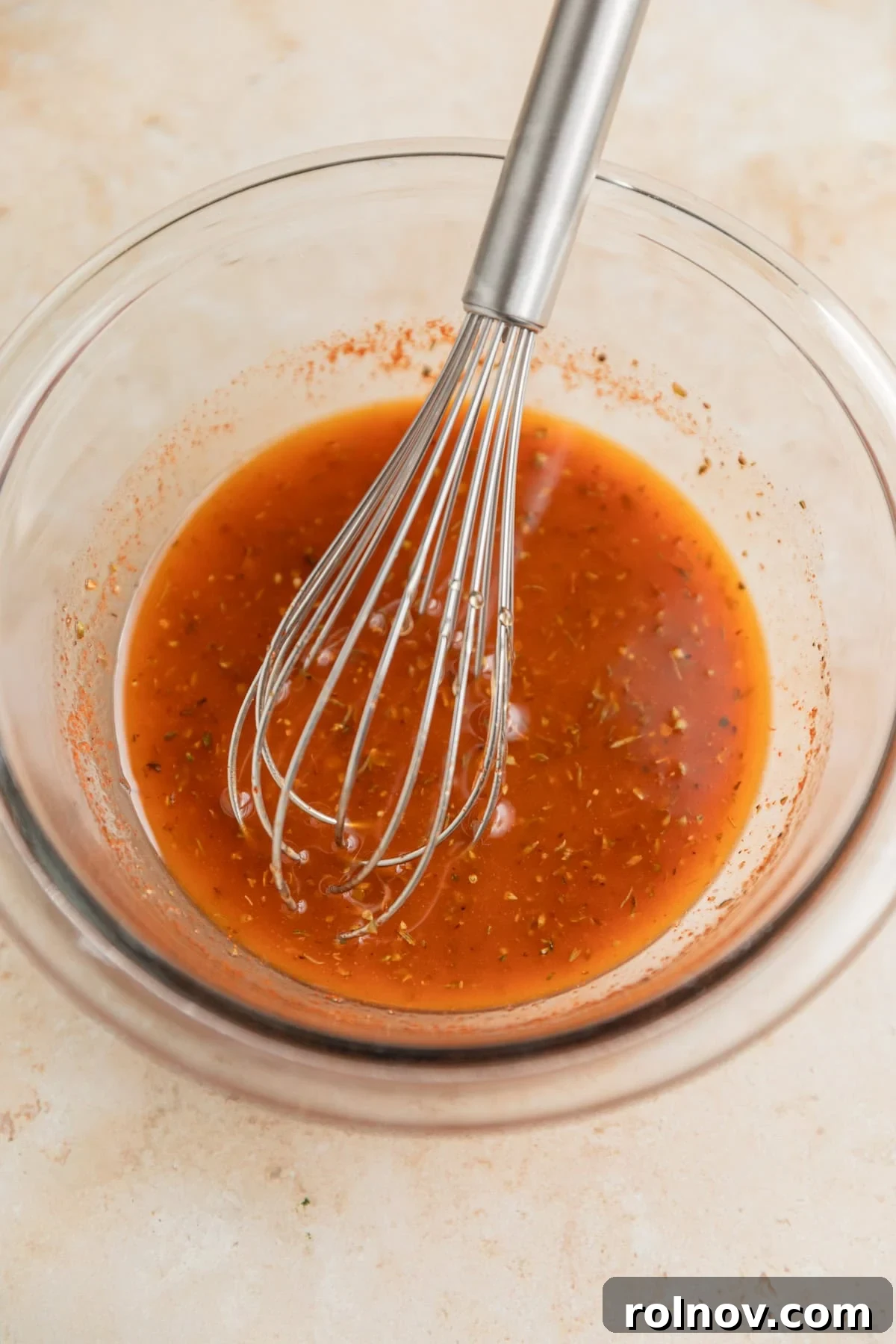 Mediterranean marinade with whisk in glass bowl.