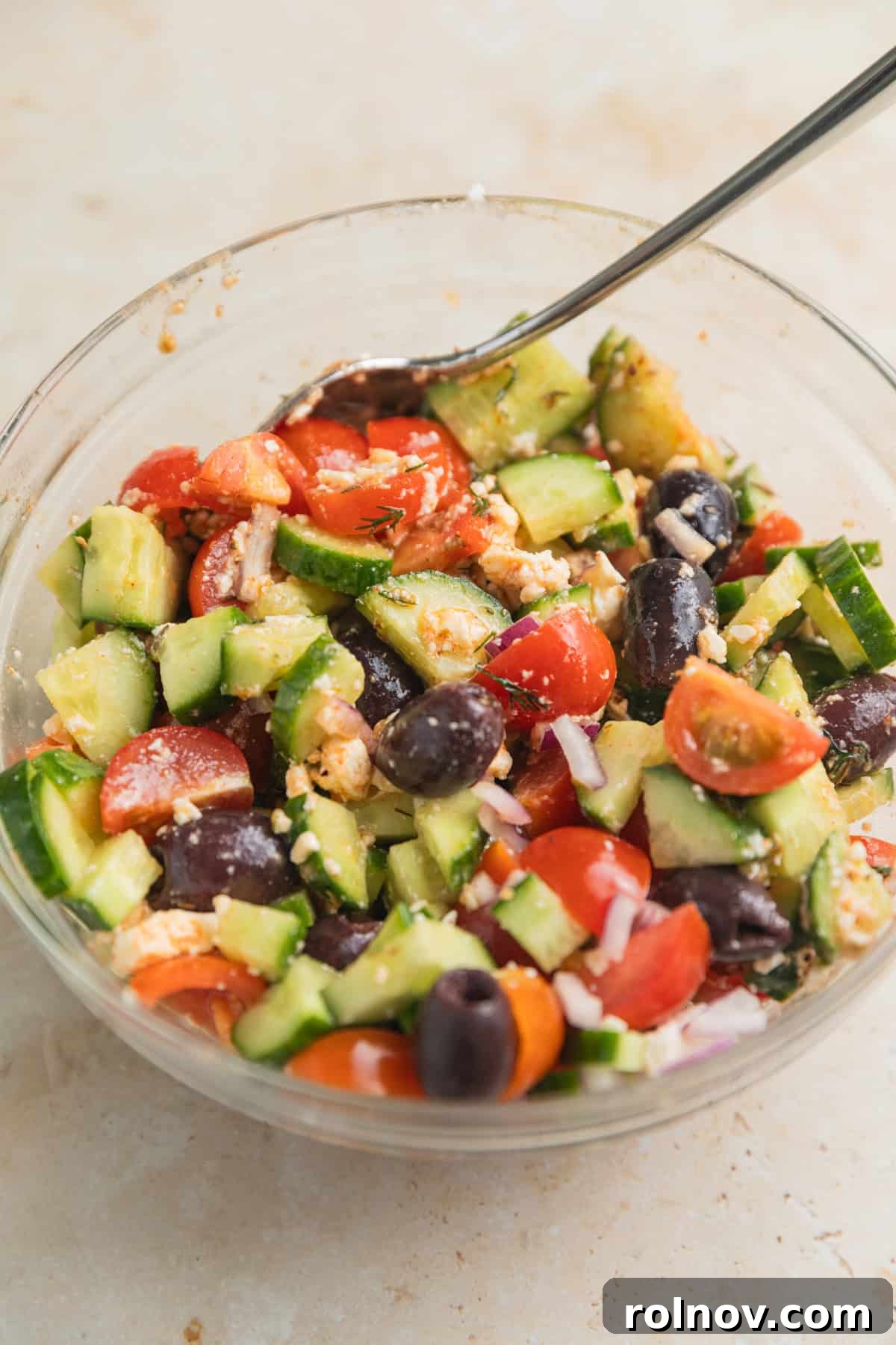 Cucumber feta salad in glass bowl with spoon.