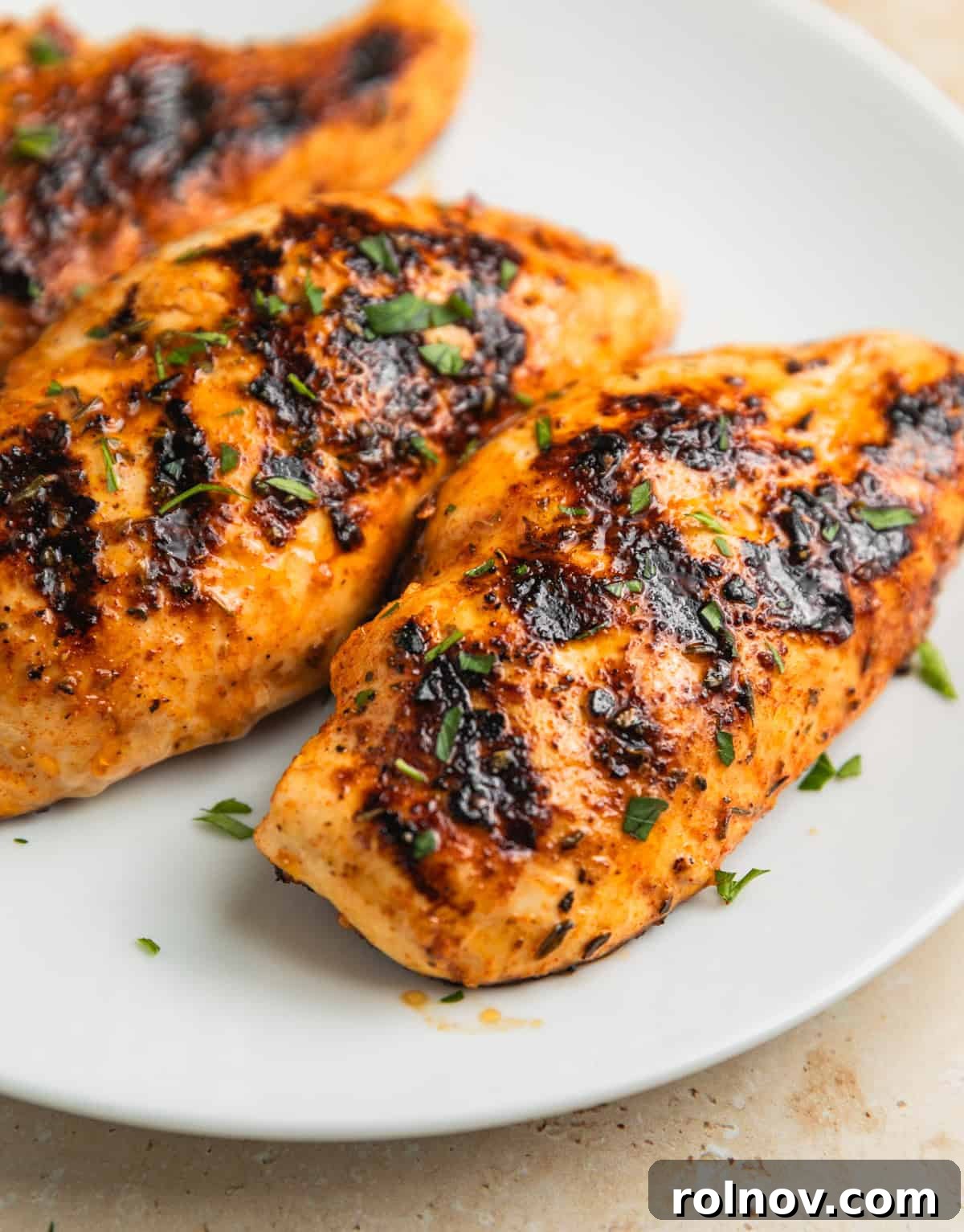 White plate with grilled mediterranean chicken resting.