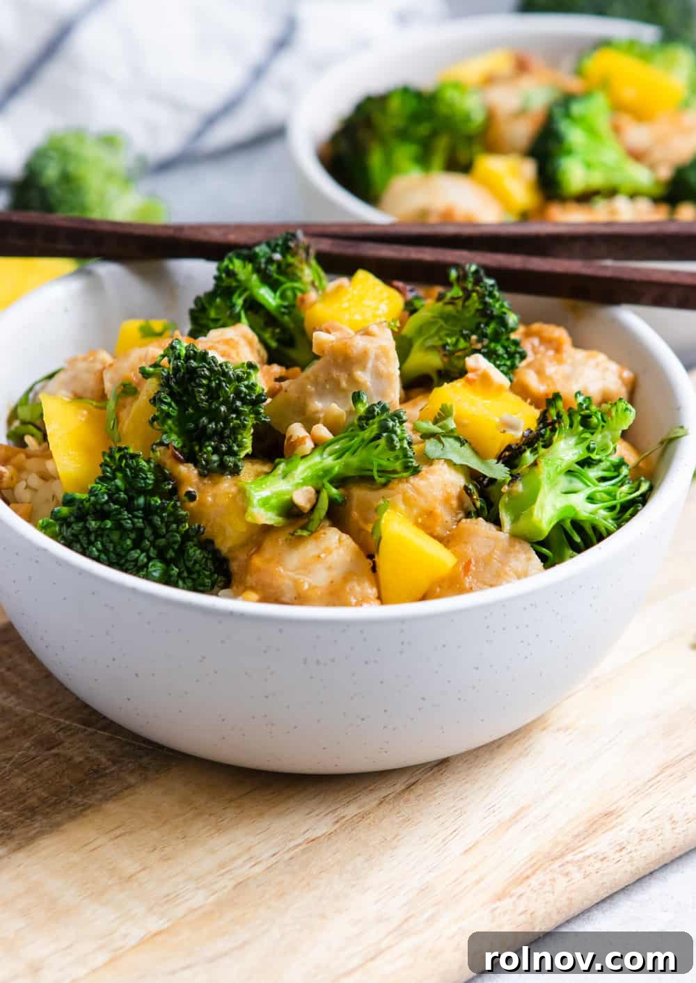 Exotic Mango Peanut Chicken Stir Fry 4 Peanut Mango Chicken and Broccoli Stir Fry served in a ceramic bowl with chopsticks, ready to eat.