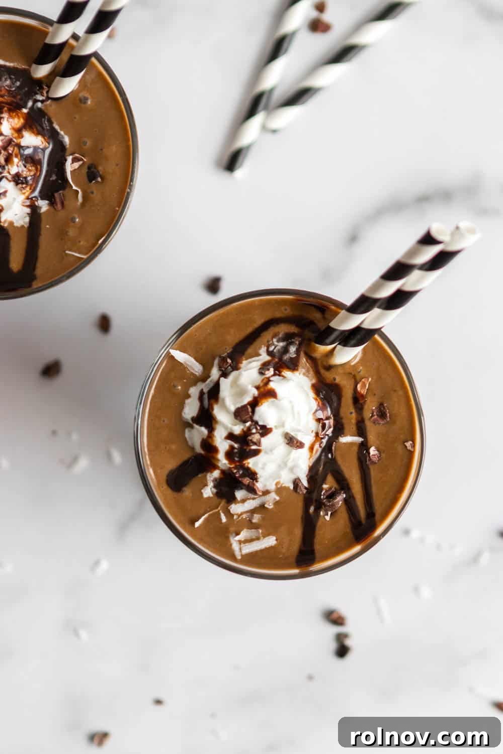Overhead shot of two almond chocolate coconut smoothies with rich chocolate sauce drizzled on top and a dollop of whipped cream.