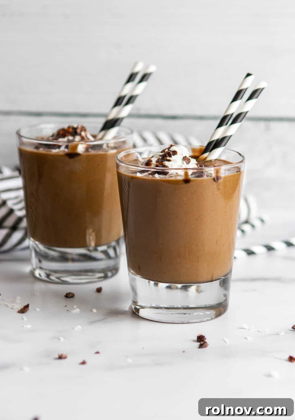 Two almond joy smoothies with whipped cream and chocolate sauce, ready to be enjoyed.