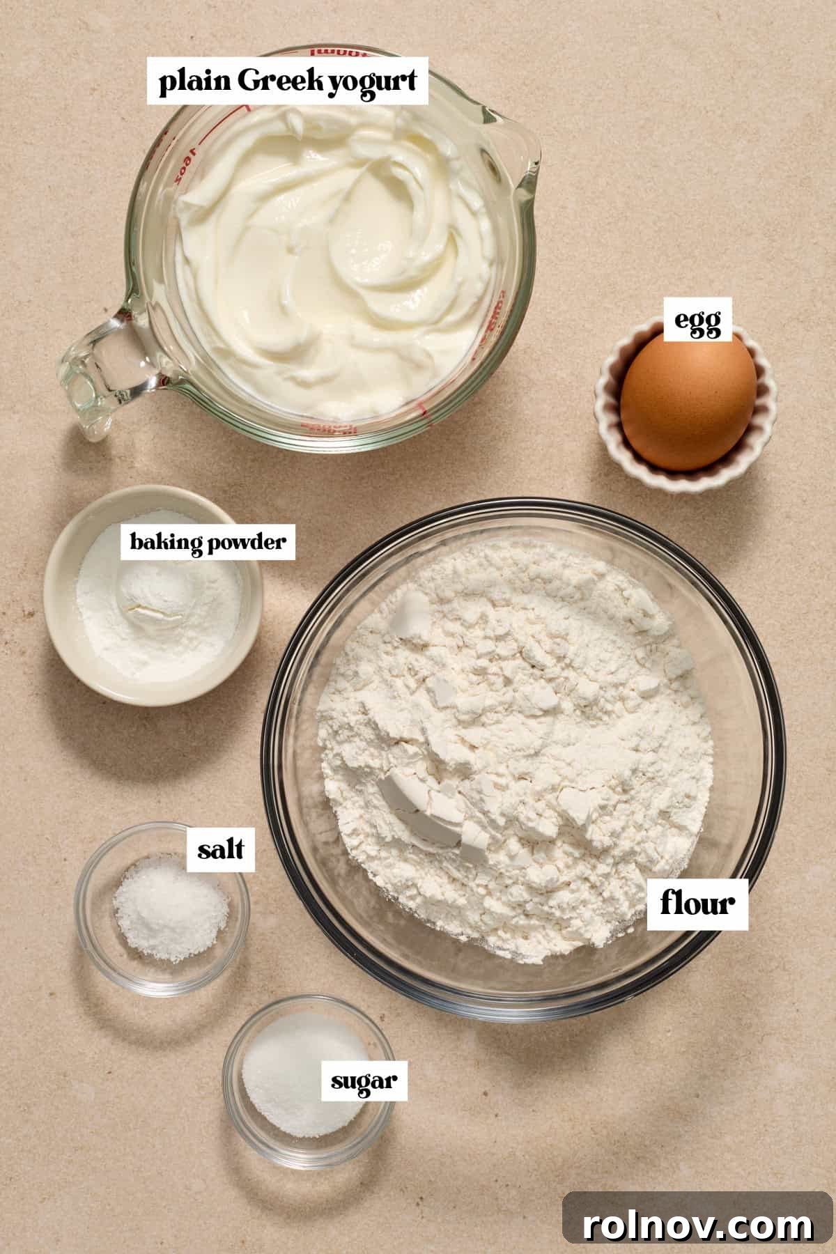 Key Ingredients for Greek Yogurt Bagels Essential ingredients like flour, plain Greek yogurt, and an egg laid out on a clean surface, ready for making bagels.