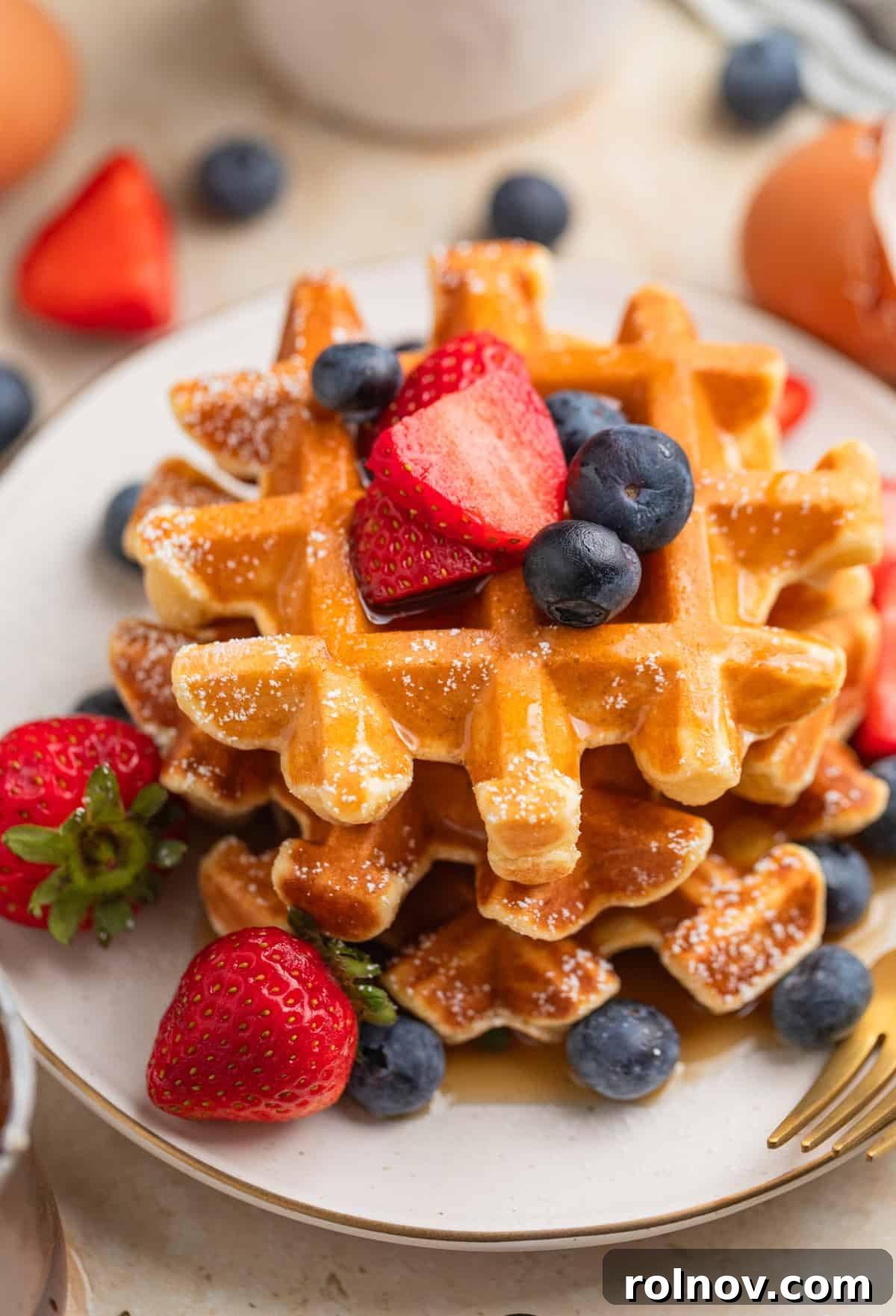 Cottage Cloud Waffles 2 Golden cottage cheese waffles piled high on a plate with fresh berries and maple syrup.