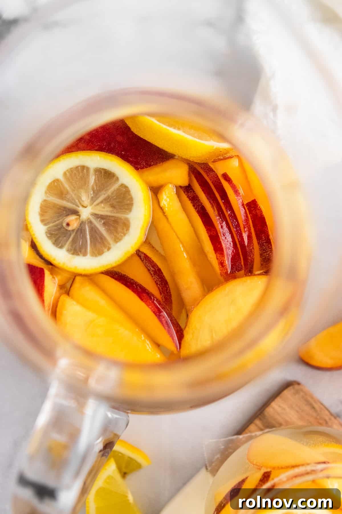 Sun-Kissed Peach Ginger Sangria 5 Overhead view of a pitcher filled with Ginger Peach White Sangria, garnished with fresh fruit, and two glasses ready for serving.