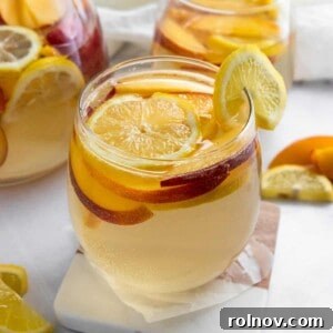 Sun-Kissed Peach Ginger Sangria 6 Ginger Peach White Sangria in a glass pitcher with fresh fruit.