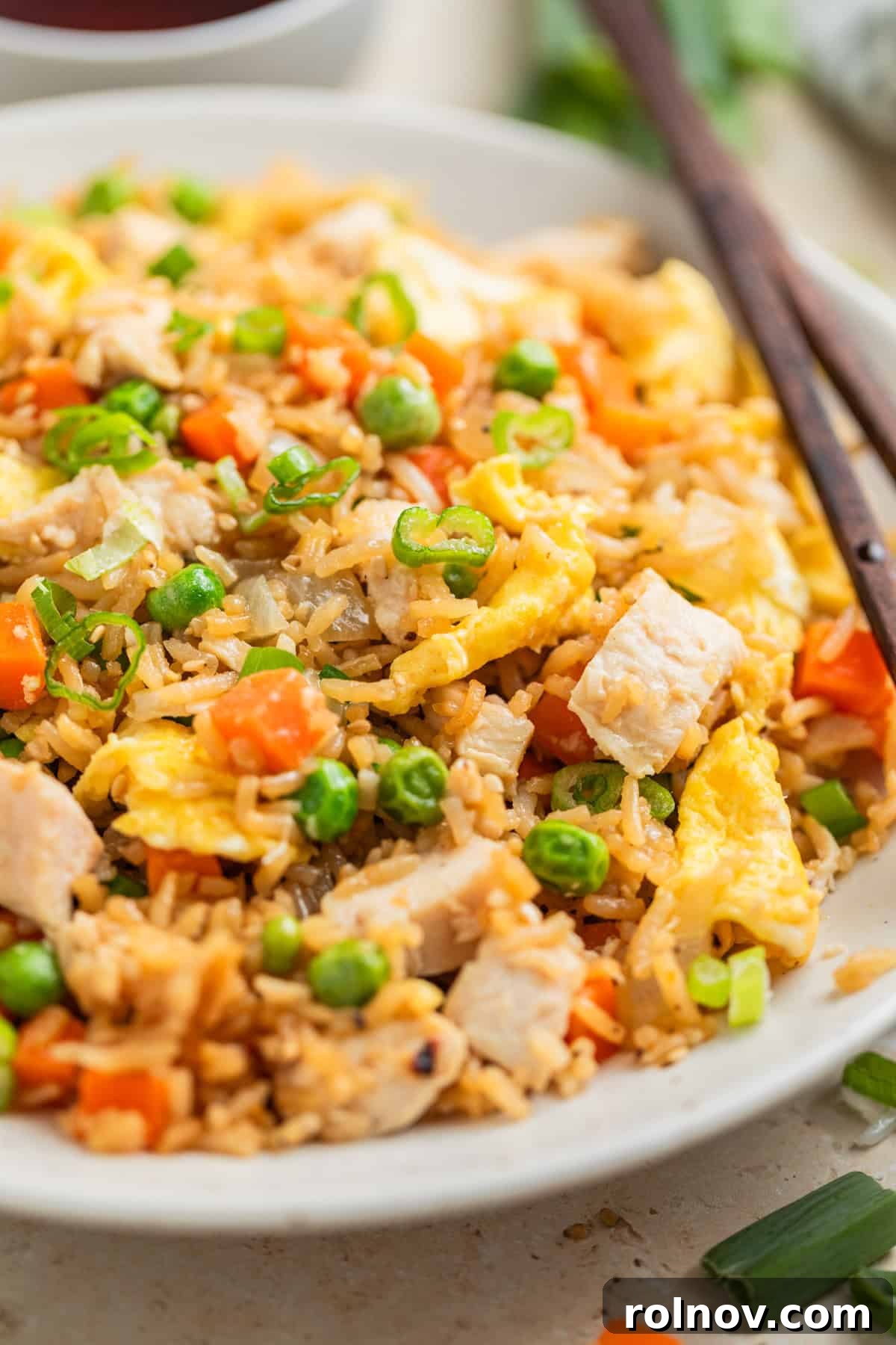 Quick Homestyle Chicken Fried Rice 2 Rotisserie chicken fried rice served on white plate with chopsticks, garnished with green onions.