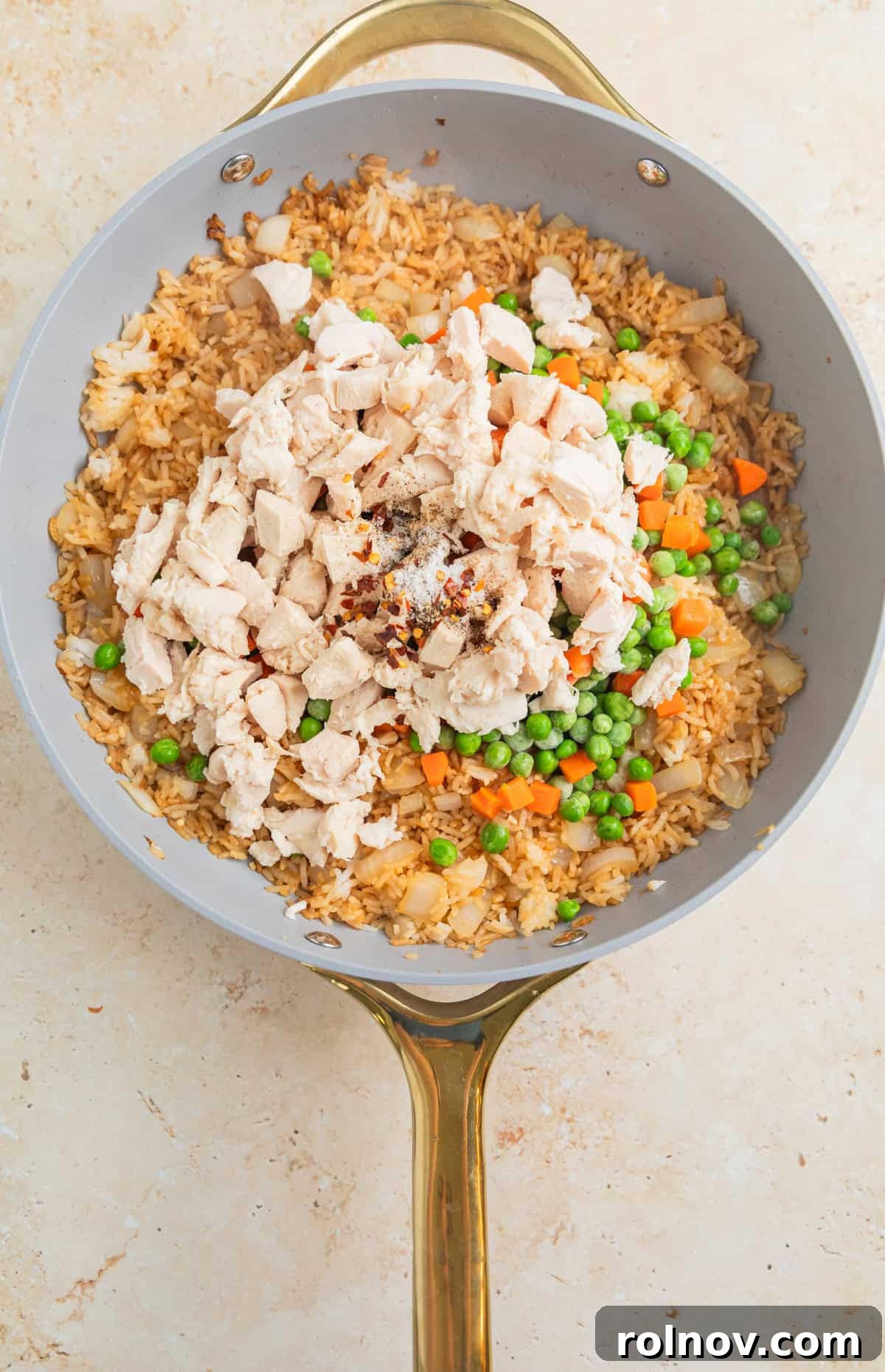 Quick Homestyle Chicken Fried Rice 7 Cooked chicken, frozen peas and carrots, minced garlic, pepper, and red chili flakes added to the fried rice in a skillet.