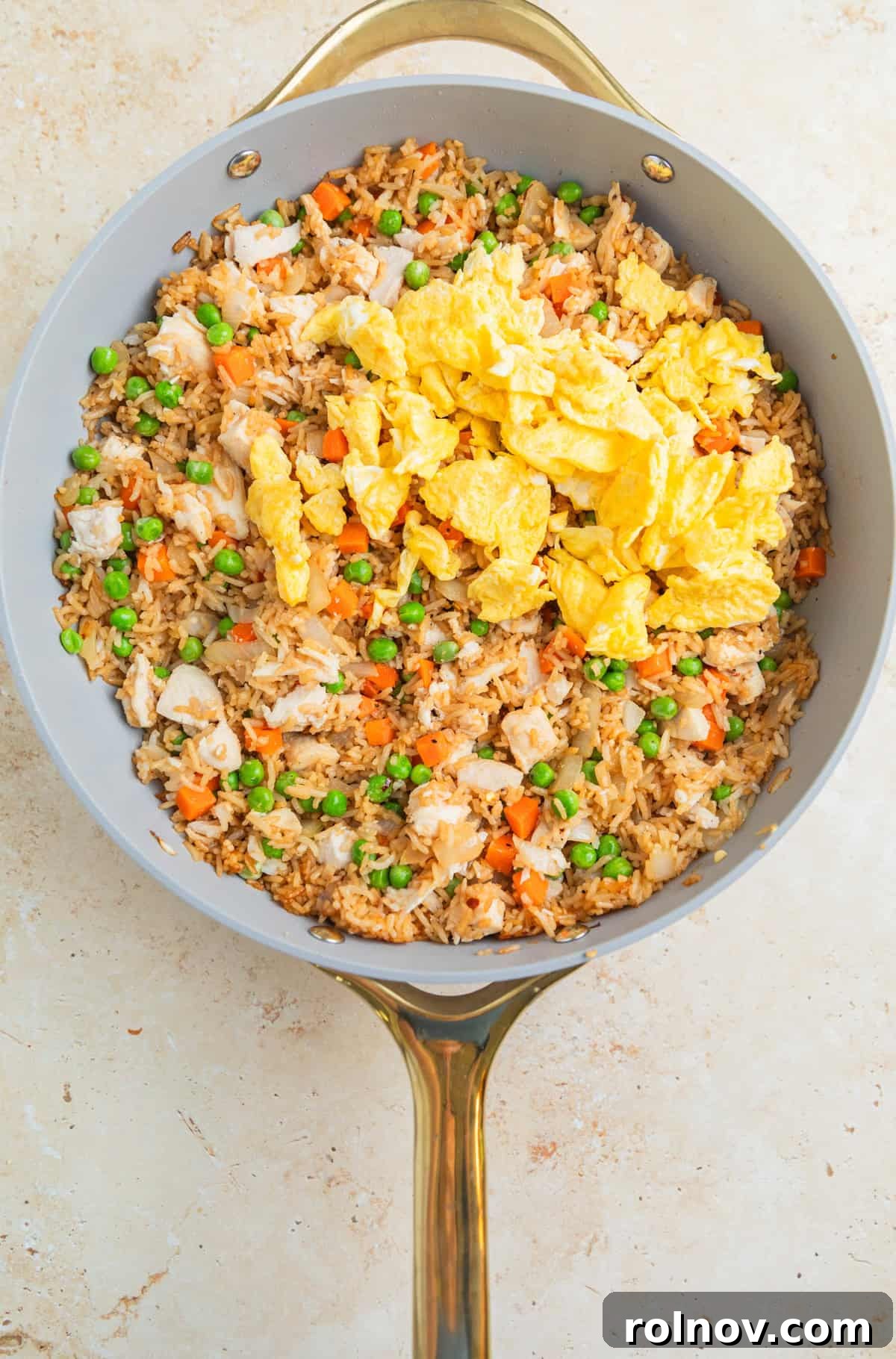 Quick Homestyle Chicken Fried Rice 8 Scrambled eggs being stirred back into the chicken fried rice in a large skillet.