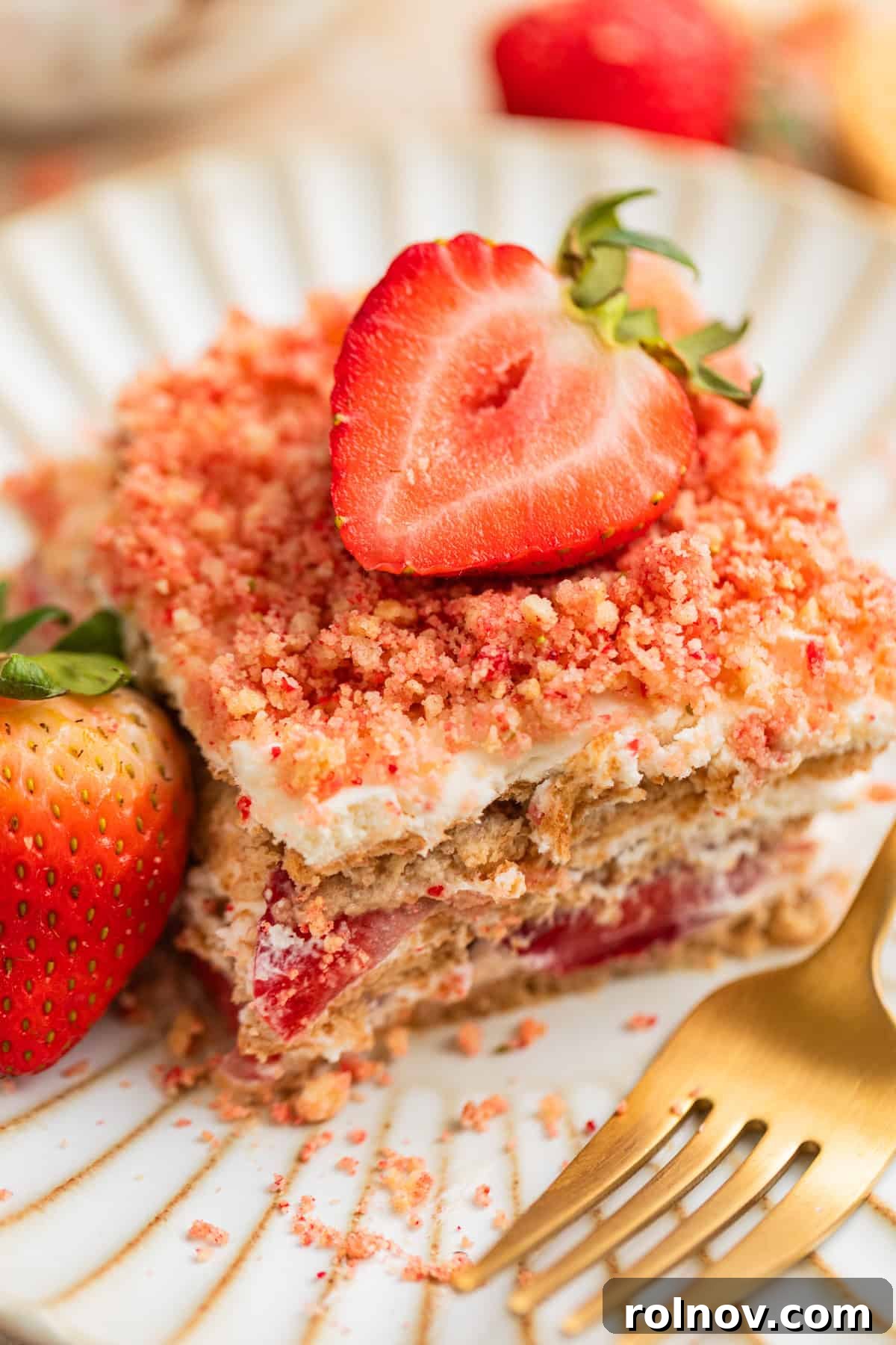 No-Bake Strawberry Dream Cake 2 A delectable slice of Strawberry Cream Cheese Icebox Cake on a plate, showcasing its beautiful layers of graham cracker, creamy filling, fresh strawberries, and crunchy topping, garnished with a fresh strawberry.