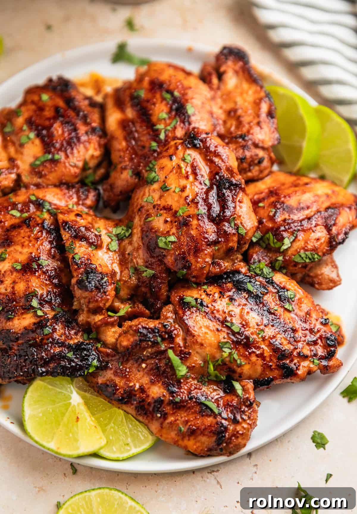 Grilled chili lime marinated chicken thighs on white plate topped with chopped cilantro.