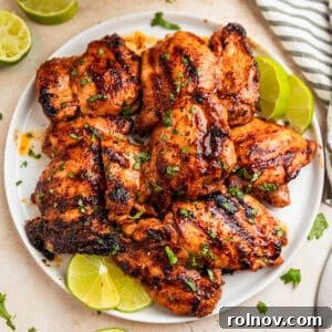 Overhead view of chili lime chicken on white plate with lime slices.