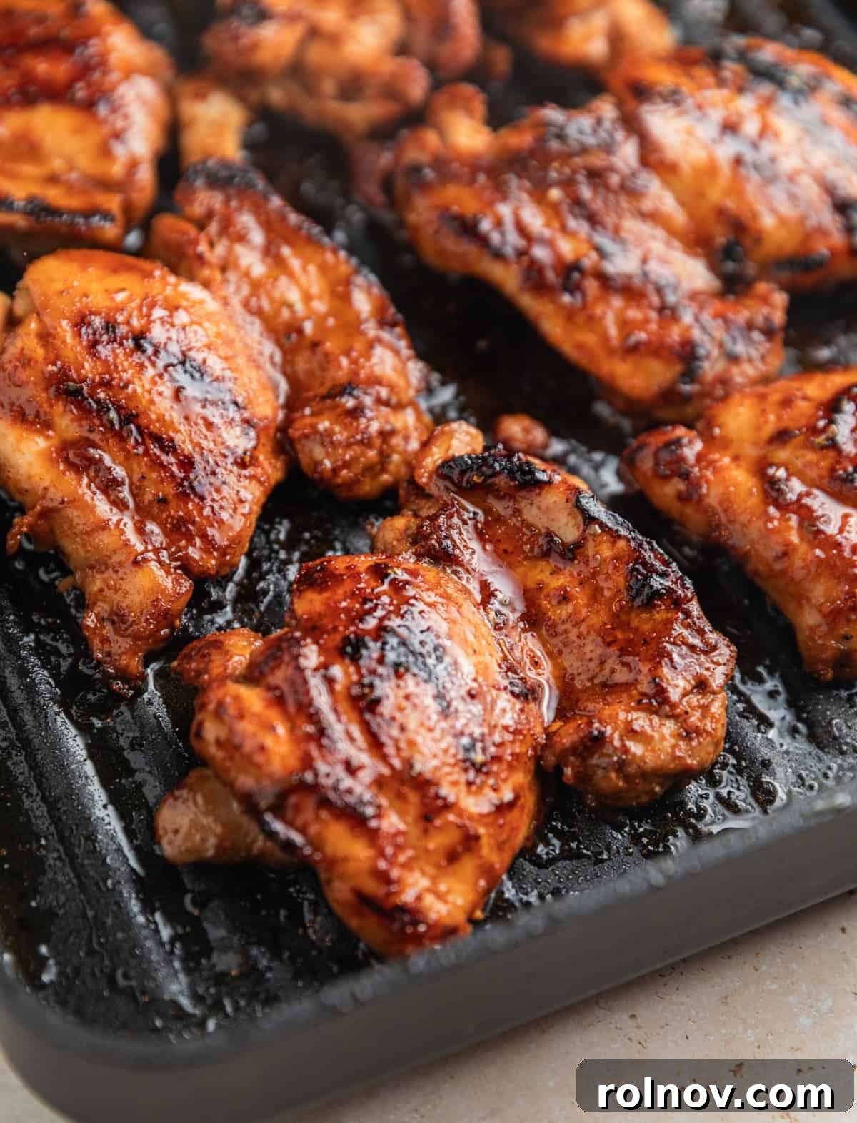 Chicken grilled on grill pan with extra marinade spread over top.