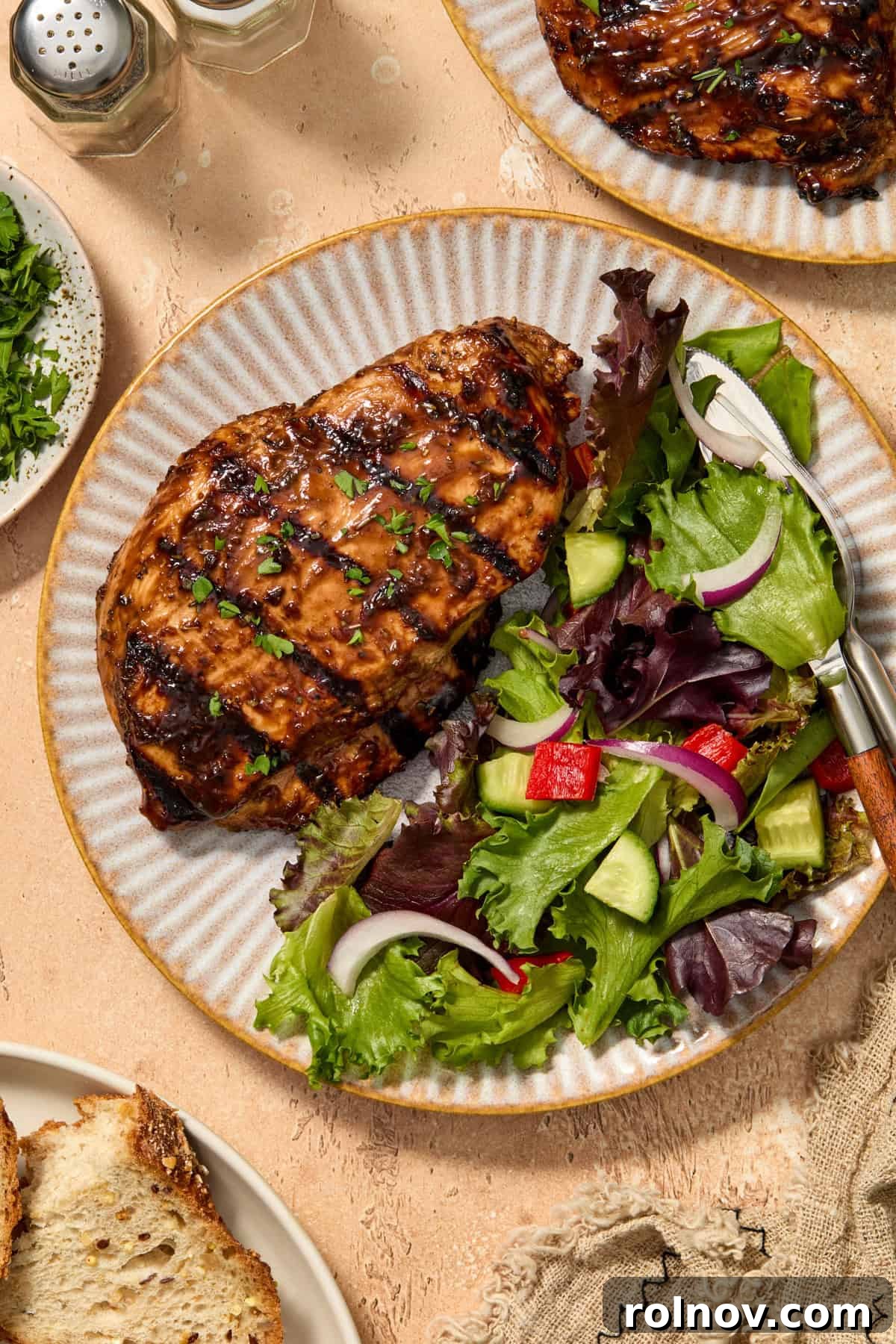Grilled Balsamic Glazed Chicken Breast 2 Balsamic grilled chicken on plate with salad and chopped parsley over top.