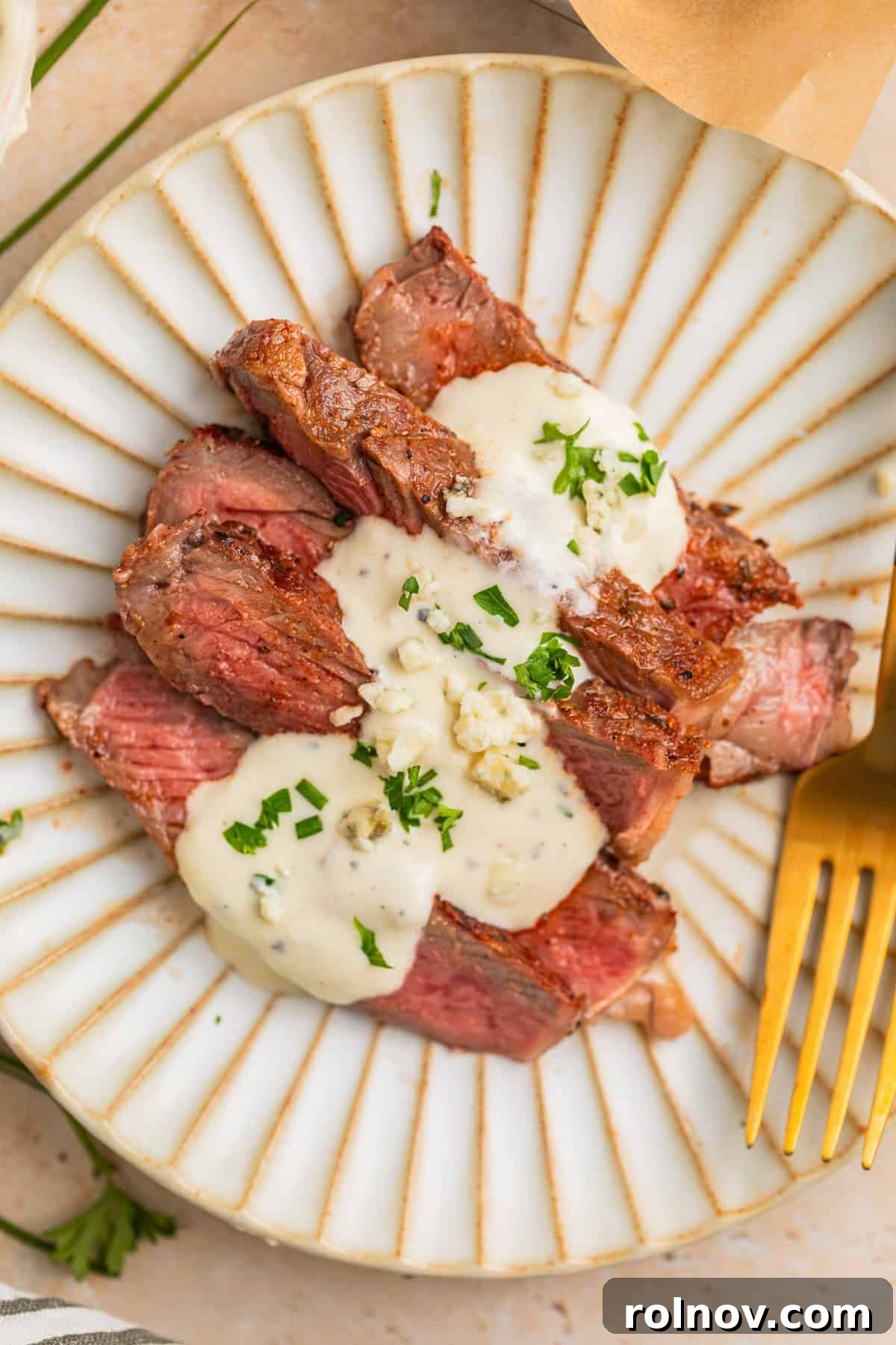 Ribeye Perfection with Gorgonzola Cream 2 Sliced grilled ribeye steak served on a plate with creamy gorgonzola cheese sauce drizzled over it.