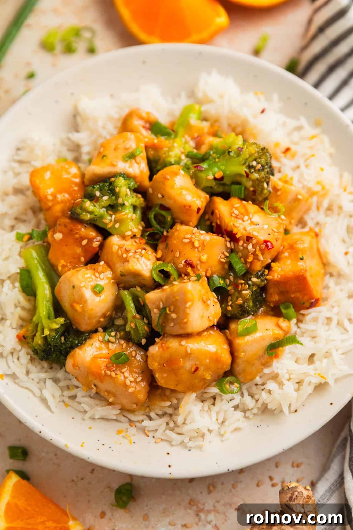 Zesty Slow Cooker Orange Chicken 2 Flavorful Crockpot Orange Chicken and Broccoli served over white rice, garnished with green onions and sesame seeds.
