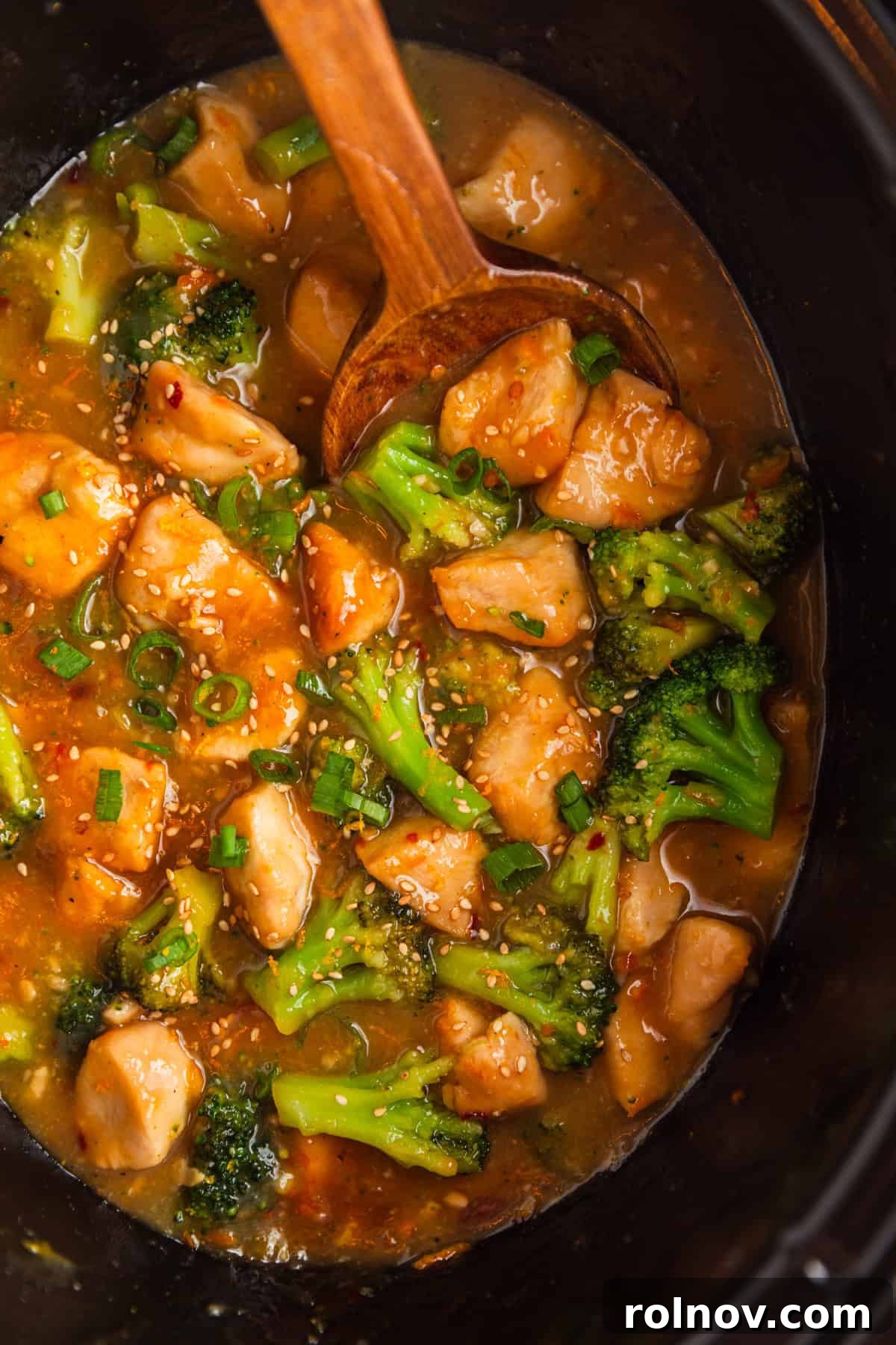 Zesty Slow Cooker Orange Chicken 12 Overhead shot of slow cooker pot brimming with delicious orange chicken and tender broccoli in a rich, glossy sauce.