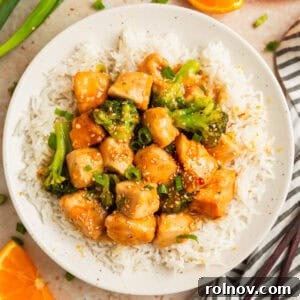 Zesty Slow Cooker Orange Chicken 13 Orange chicken and broccoli served over white rice on plate.