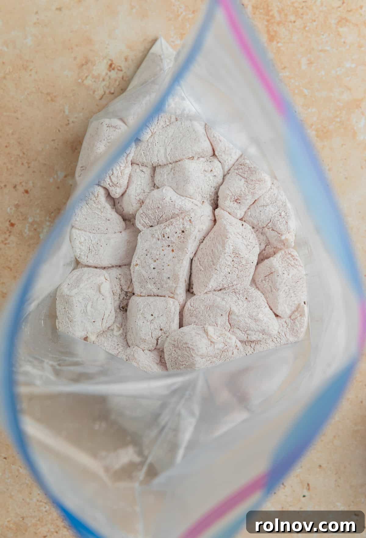 Zesty Slow Cooker Orange Chicken 6 Cubed chicken breast coated in cornstarch, salt, and pepper inside a plastic ziplock bag.