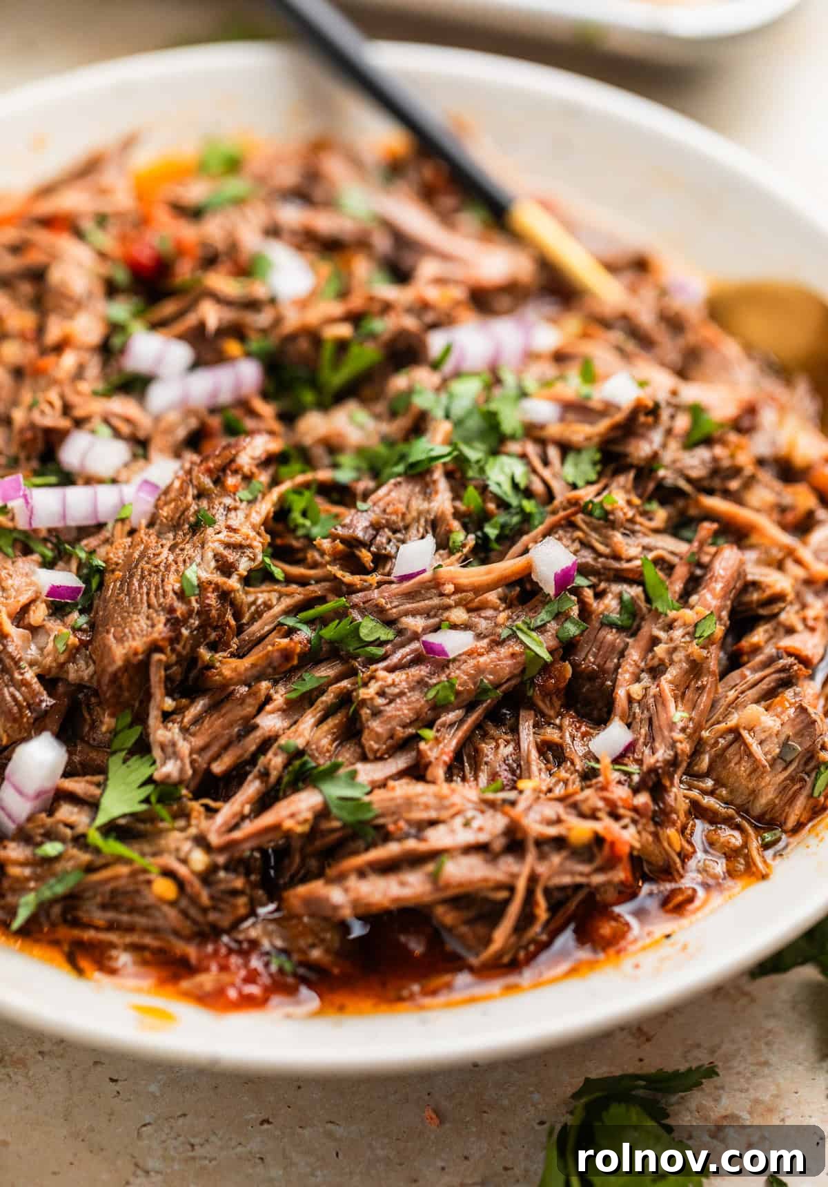 Melt In Your Mouth Slow Cooker Beef Tacos 9 Slow cooker shredded beef tacos in serving plater with spoon.