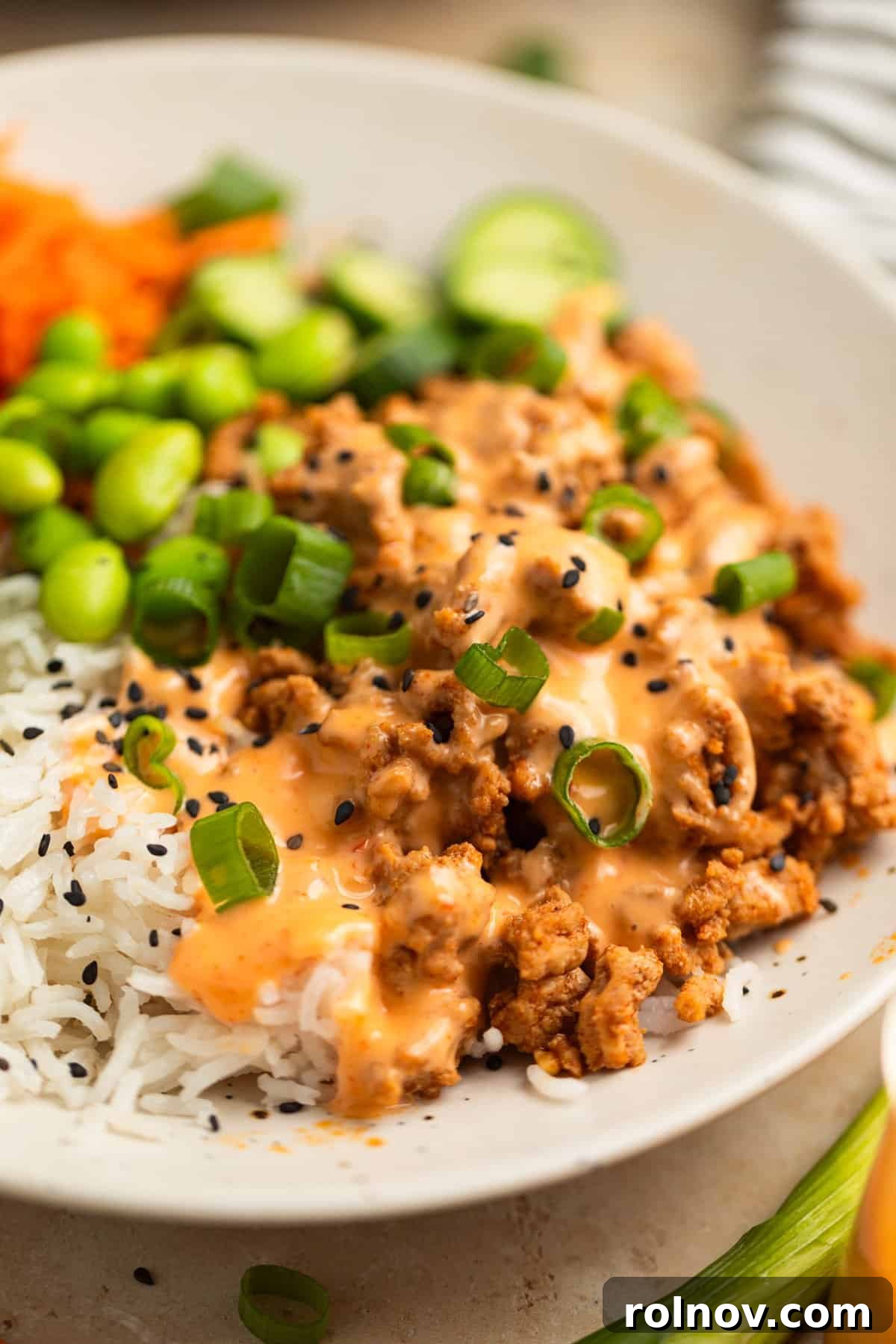 Savory Turkey Rice Power Bowls 2 A vibrant ground turkey rice bowl generously topped with creamy bang bang sauce and sprinkled with toasted sesame seeds, ready to be enjoyed.